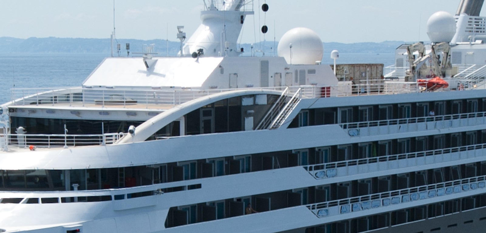 Fincantieri | Group - Business - Products - Cruise Ships - L'Austral: Modern luxury cruise ship in operation gliding through calm open waters under clear blue sky, sleek design and multiple decks, premium travel experience, serene ocean setting emphasizes elegance and scale, ideal for leisure or exploration.