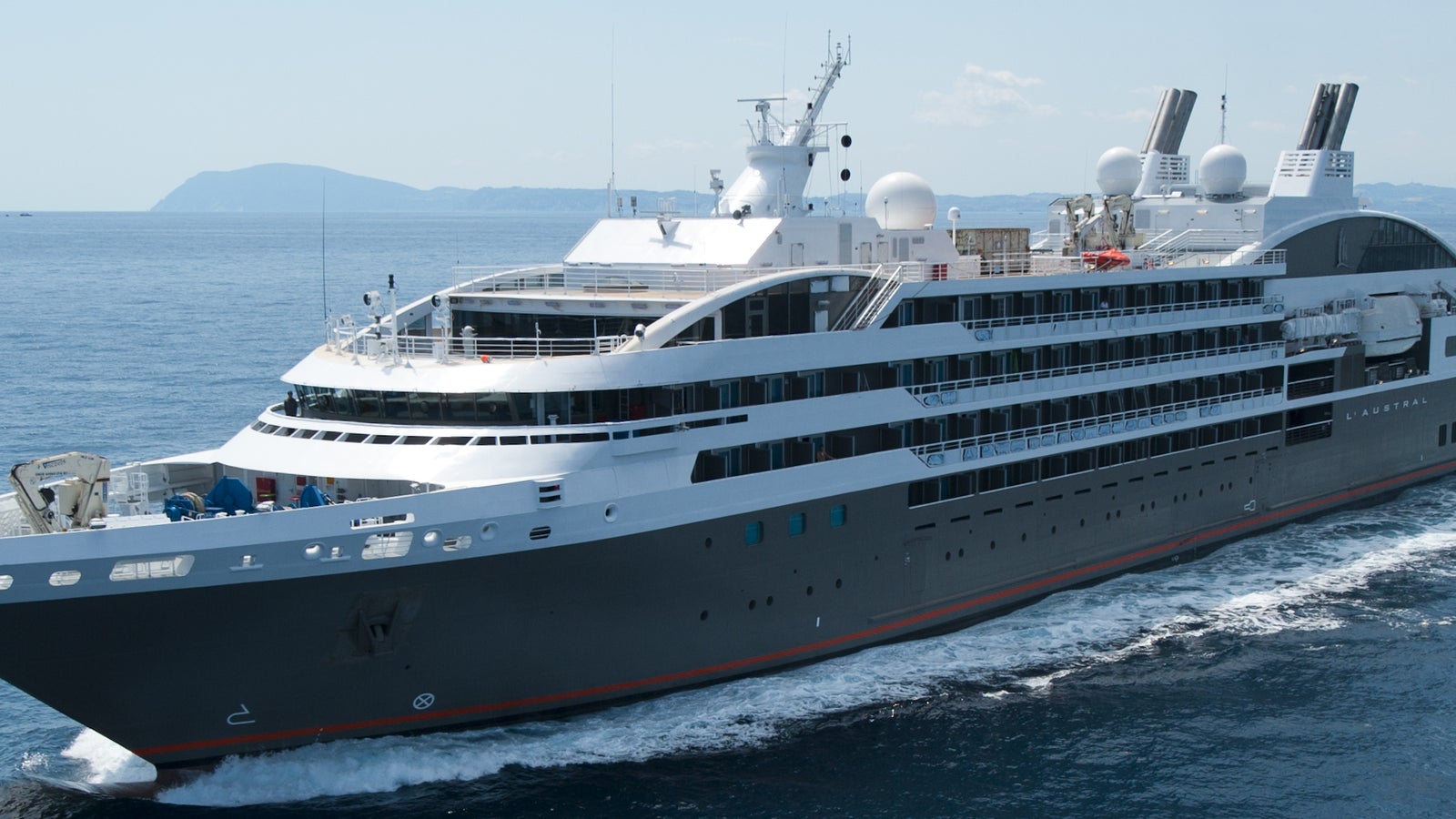 Fincantieri | Group - Business - Products - Cruise Ships - L'Austral: Side view of L'Austral cruise ship in operation navigating open sea, anthracite grey linear profile hull, multiple passenger decks, visible funnels and lifeboats positioned along sides.