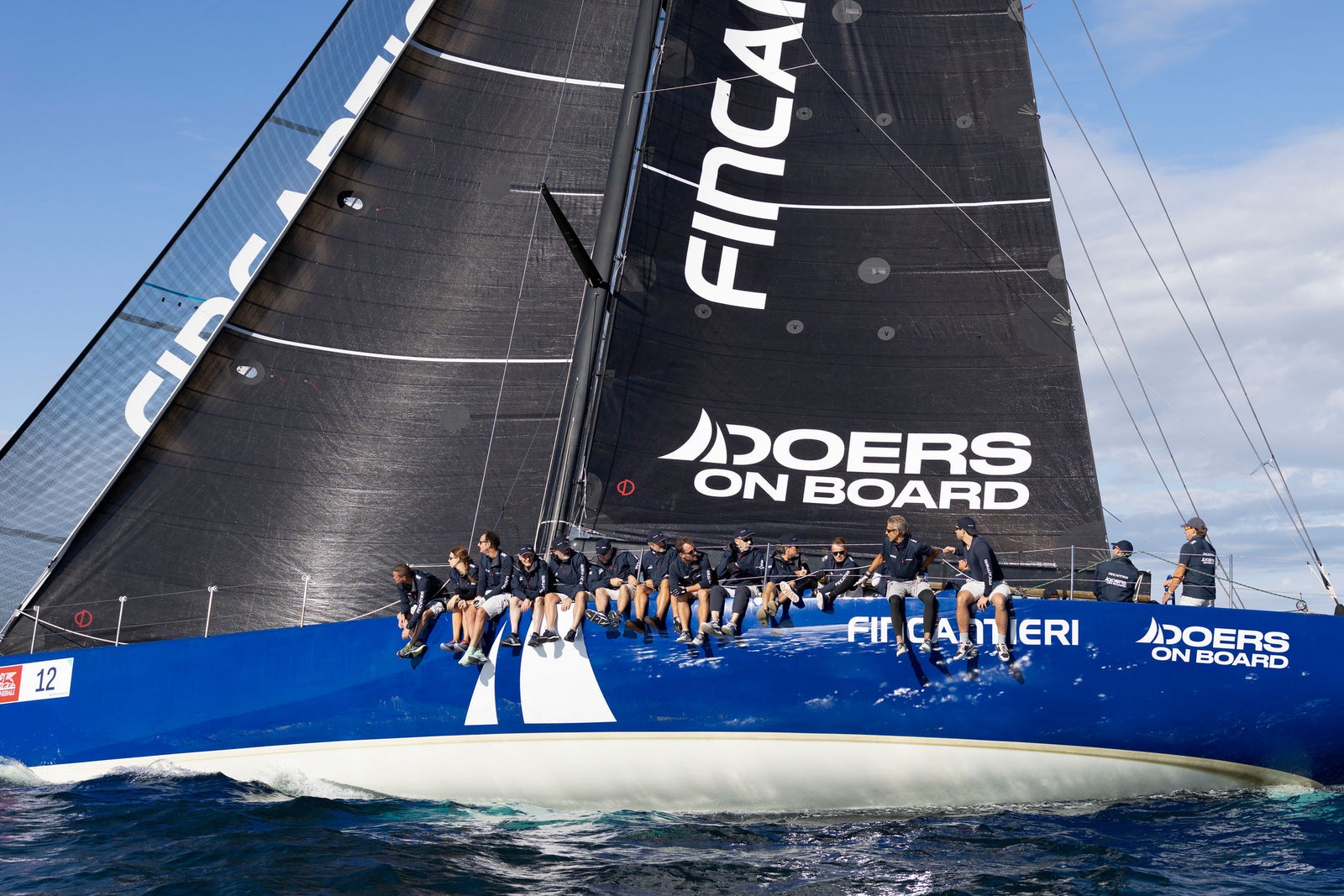Crew sailing high-performance racing yacht at sea