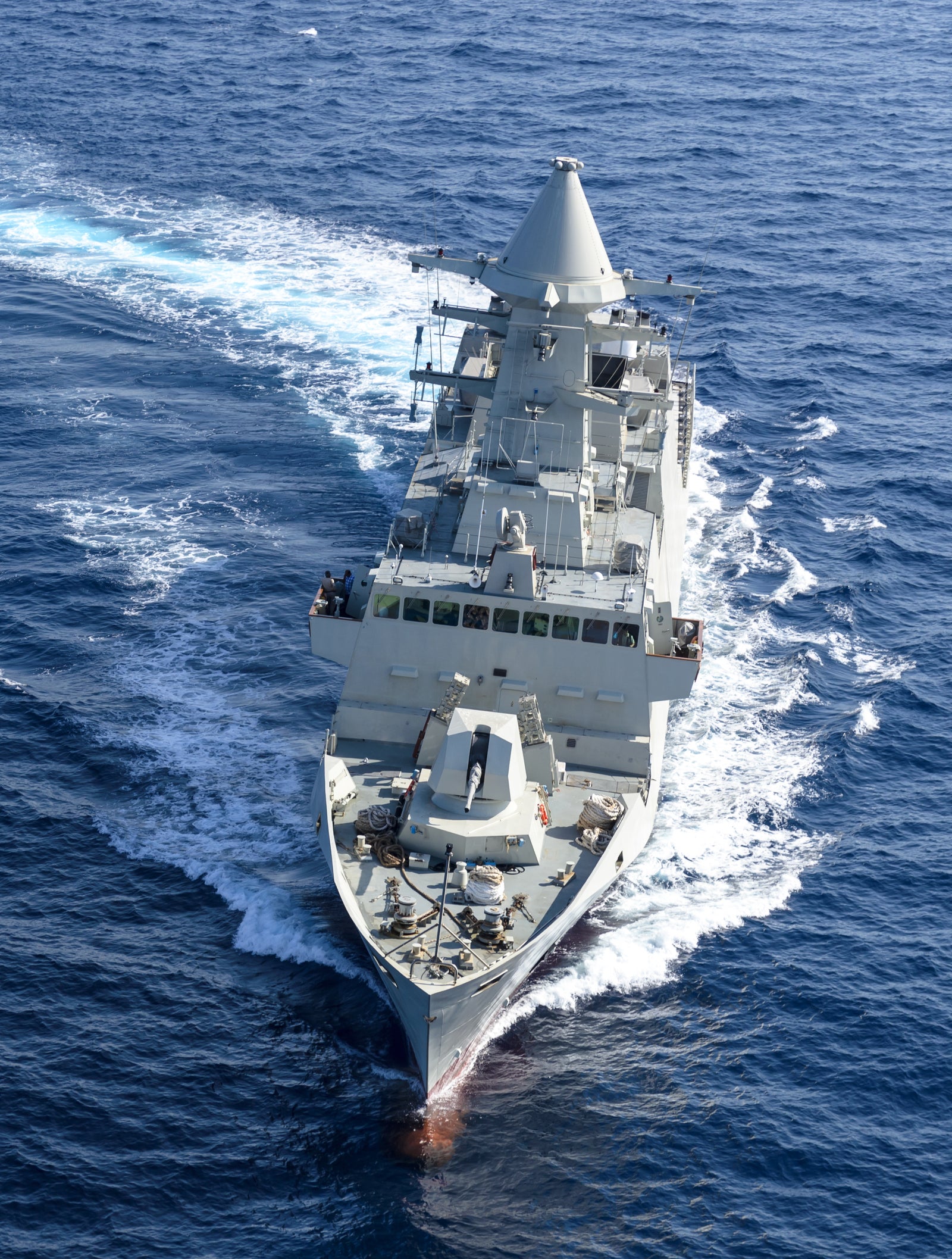 Fincantieri | Group - Business - Products - Defence Vessels - Patrol Vessels - Abu Dhabi class: Side view of operational ship underway, streamlined design, advanced radar and armaments visible on deck, prominent white wake.