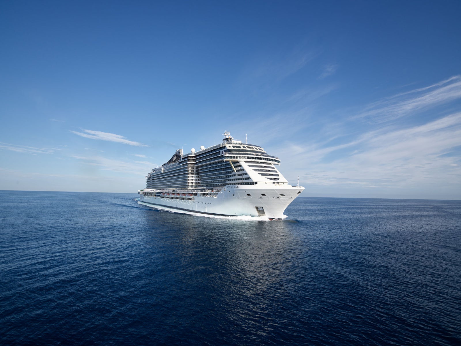 Fincantieri | Servizi - Riparazioni e Trasformazioni navali: Vista laterale della nave da crociera moderna operativa in navigazione su acque calme, multipli ponti e design elegante, ambiente marittimo sereno.