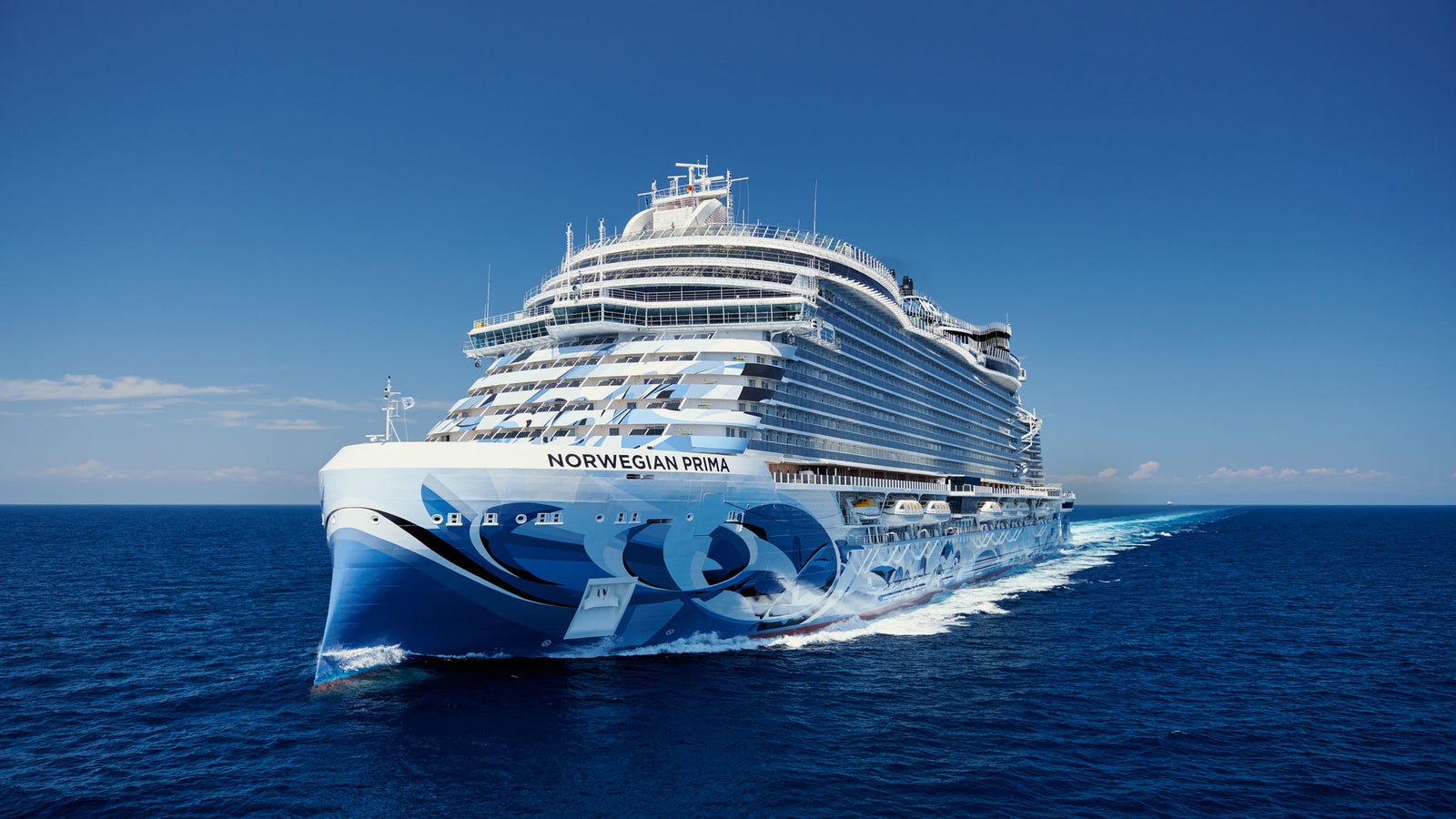 Fincantieri | Group - Business - Products - Cruise Ships - Norwegian Prima: Side view of Norwegian Prima cruise ship in operation, name clearly visible on hull with wave graphic motifs, luxurious design.