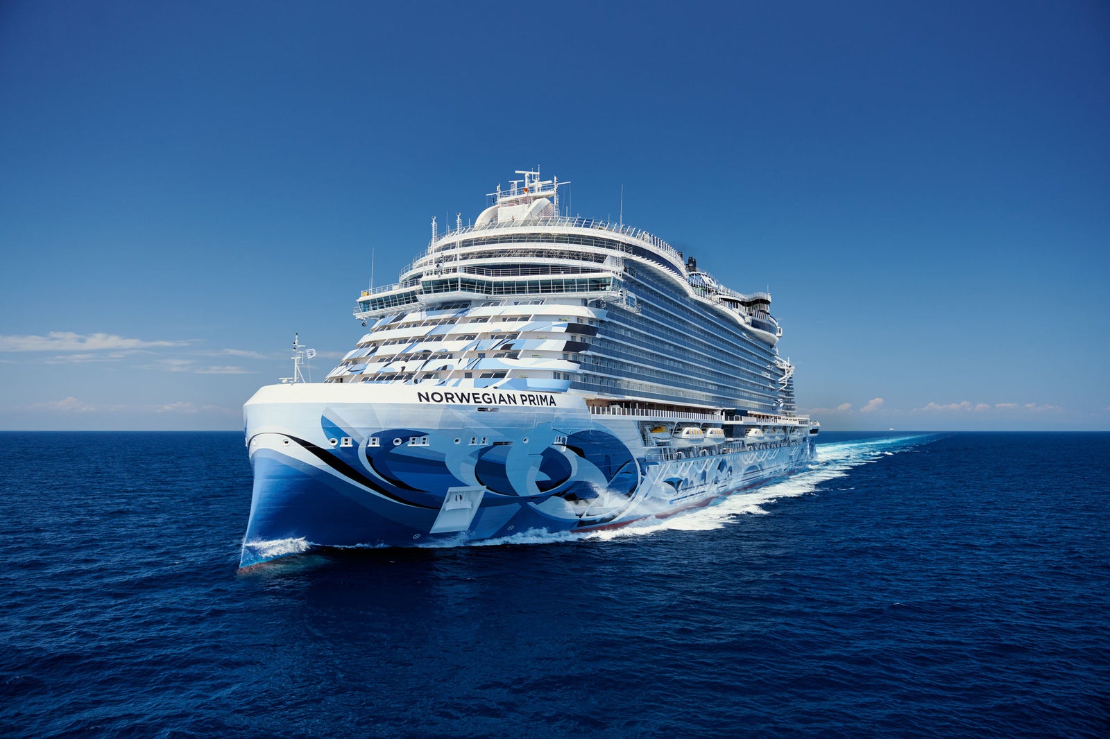 Fincantieri | Group - Business - Products - Cruise Ships - Norwegian Prima: Side view of Norwegian Prima cruise ship in operation, name clearly visible on hull with wave graphic motifs, luxurious design.