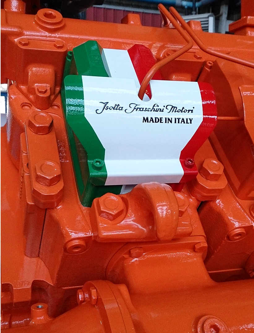 Fincantieri | Group - Subsidiaries and Affiliates - Isotta Fraschini Motori: Close-up of Isotta Fraschini engine component painted in Italian flag colors, 'Isotta Fraschini Motori' and 'Made in Italy' text clearly visible; surrounding machinery painted bright orange, strong contrast with green, white, and red design.