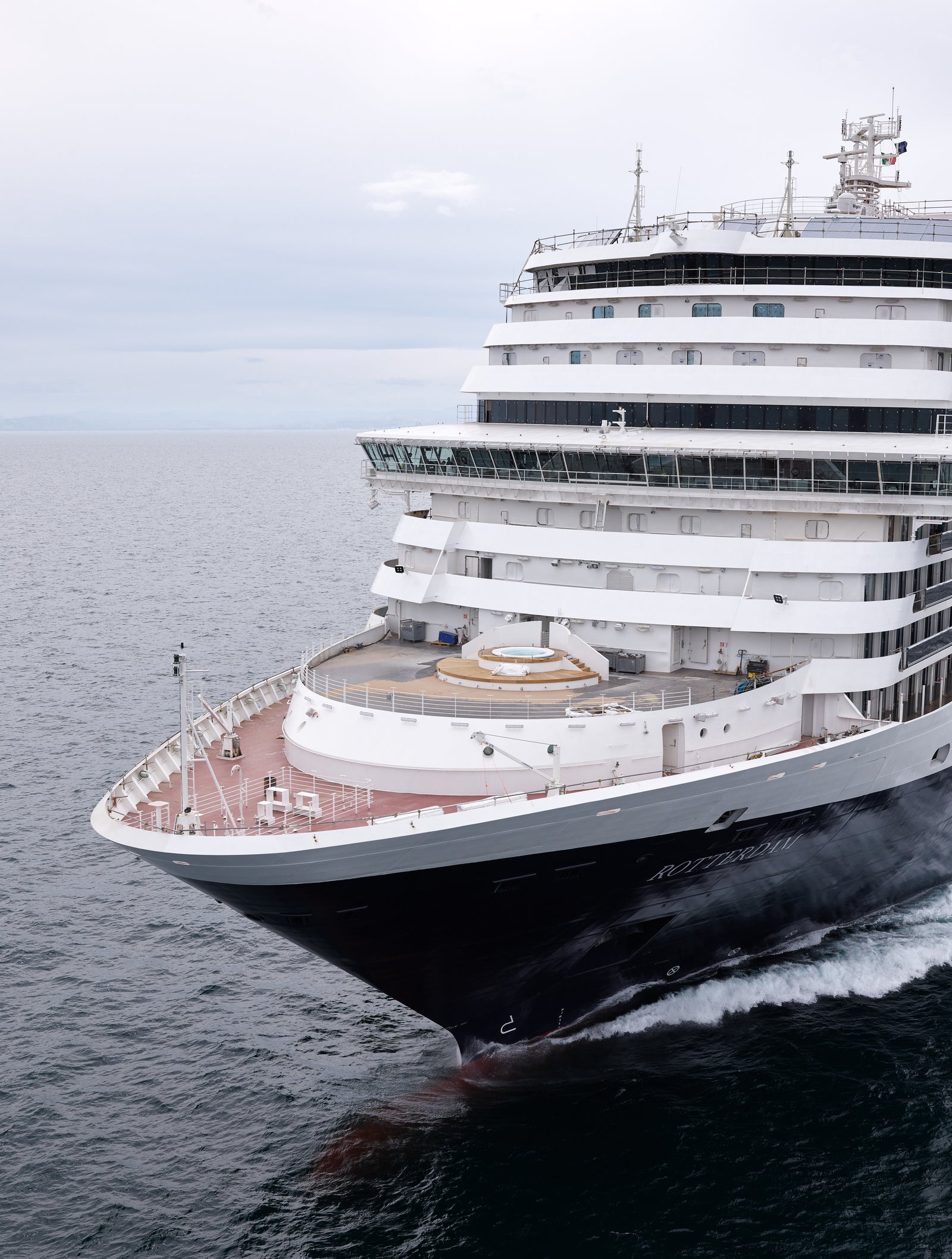 Fincantieri | Group - Business - Products - Cruise Ships - Rotterdam: Modern operational cruise ship sailing on calm open waters under overcast sky, multiple decks, large windows, lifeboats along sides and whirlpool pool on deck.