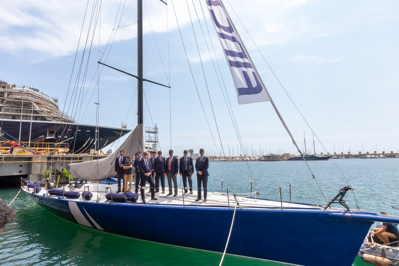 Business delegation standing on docked sailboat