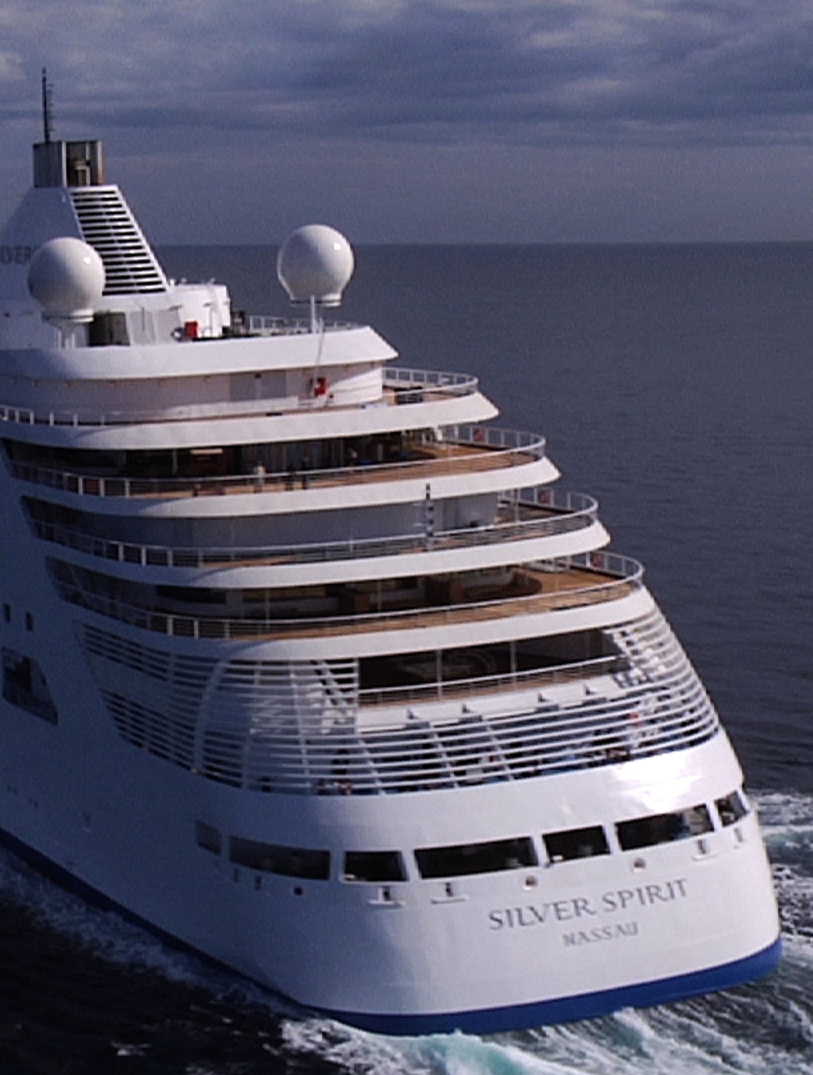 Fincantieri | Group - Business - Products - Cruise Ships - Silver Spirit: Large operational cruise ship with modern refined design, sailing on calm waters under cloudy sky with visible wake, multiple decks with large windows and spherical antennas, 'Silver Spirit' name clearly visible on hull, scene evokes luxury, relaxation, and maritime adventure.