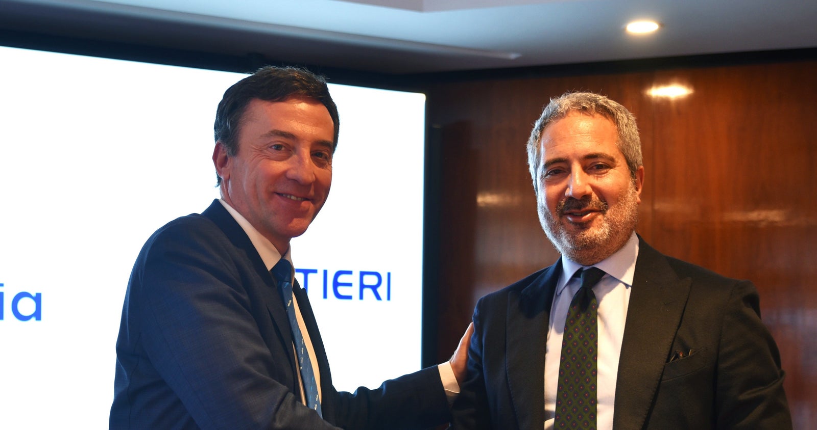 Newsroom - Press releases - 2026 - Fincantieri Group: Navantia and Fincantieri strengthen their cooperation to advance the European Patrol Corvette (EPC) programme: navantia and fincantieri executives in suits shake hands in front of presentation screen during epc partnership event.