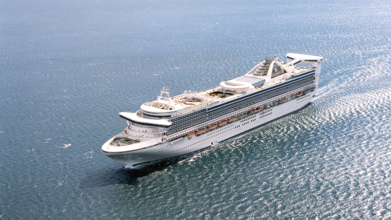Fincantieri | Group - Business - Products - Cruise Ships - Grand Princess: Side view of Grand Princess cruise ship in operation navigating, multiple decks with outdoor spaces and pools, modern leisure-oriented design.