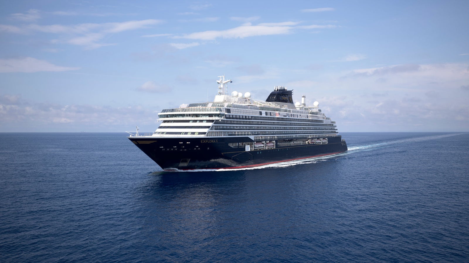 Fincantieri | Group - Business - Products - Cruise Ships - EXPLORA II: Side view of operational cruise ship in navigation, sleek black and white design, multiple decks and visible amenities, name Explora X clearly visible on hull.