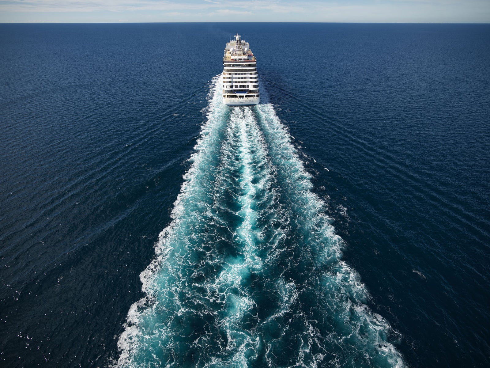 Newsroom - Comunicati stampa - 2025 - Gruppo Fincantieri: Fincantieri costruirà una nuova nave da crociera ultra-lusso per Regent Seven Seas Cruises: Nave da crociera vista da poppa in navigazione in mare aperto, lunga scia sull’acqua e orizzonte libero, simbolo di innovazione e lusso marittimo.