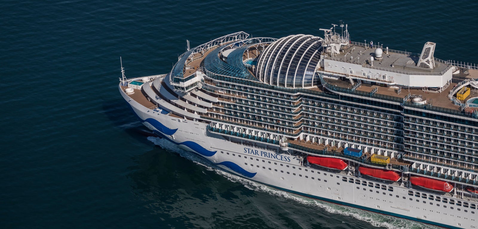 Fincantieri | Gruppo - Business - Prodotti - Navi da Crociera - Star Princess: Elegant cruise ship Discovery Princess in operation, navigating calm open waters, modern design with multiple decks and curved architectural elements, name visible on side, clear sky.