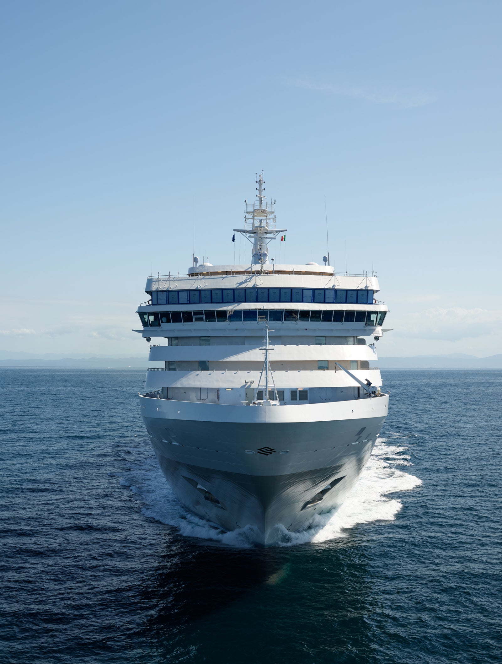 Fincantieri | Group - Business - Products - Cruise Ships - Silver Dawn: White cruise ship in operation gliding across calm deep blue ocean under clear sky, multiple decks and visible windows, setting highlights sea vastness and journey tranquility.
