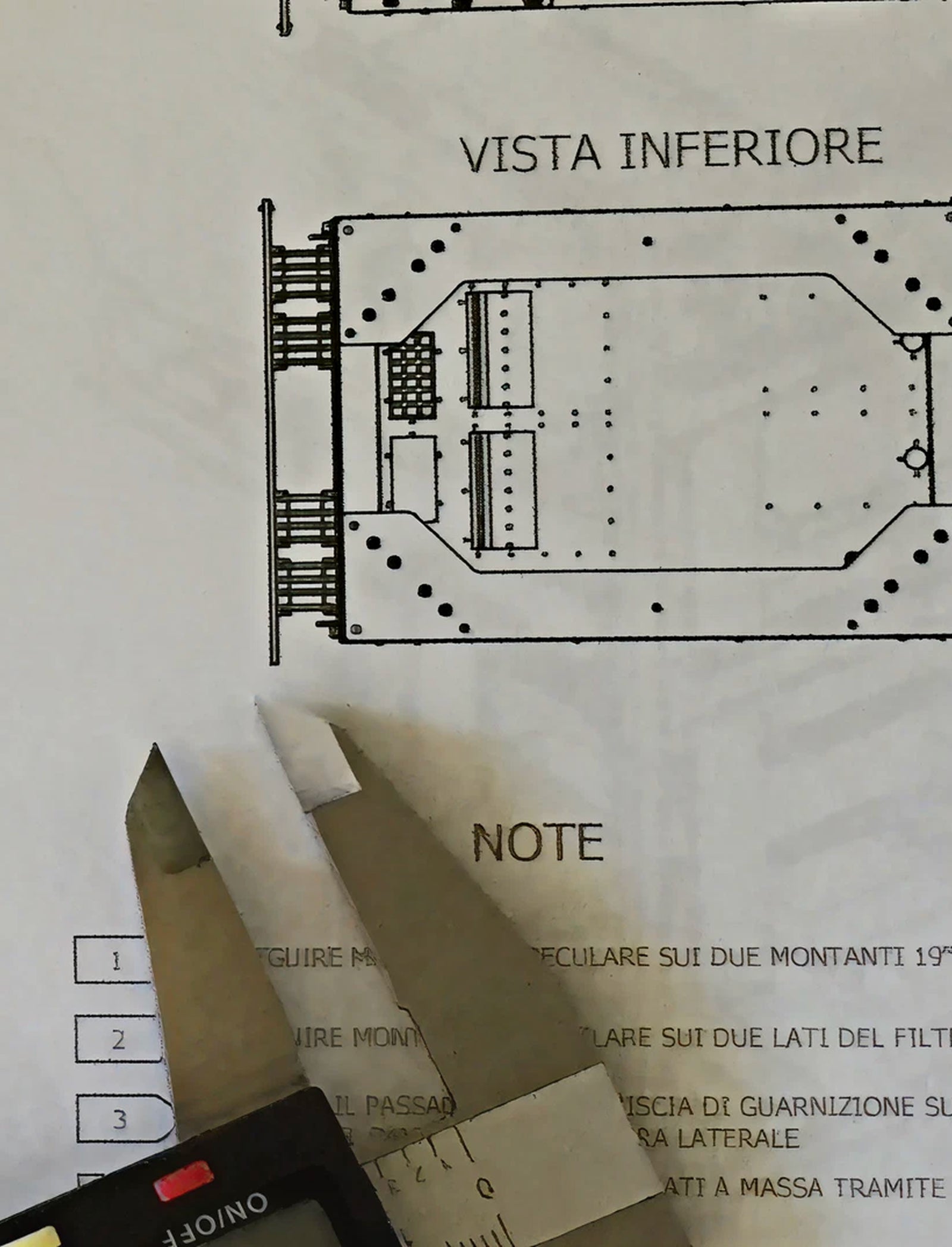 Fincantieri | Group - Subsidiaries and Affiliates - SLS: Detailed technical blueprint labeled ‘Vista Inferiore’ displayed alongside a precision caliper tool; structural diagrams and Italian notes with visible numeric annotations, caliper partially visible suggesting a measurement or engineering context.