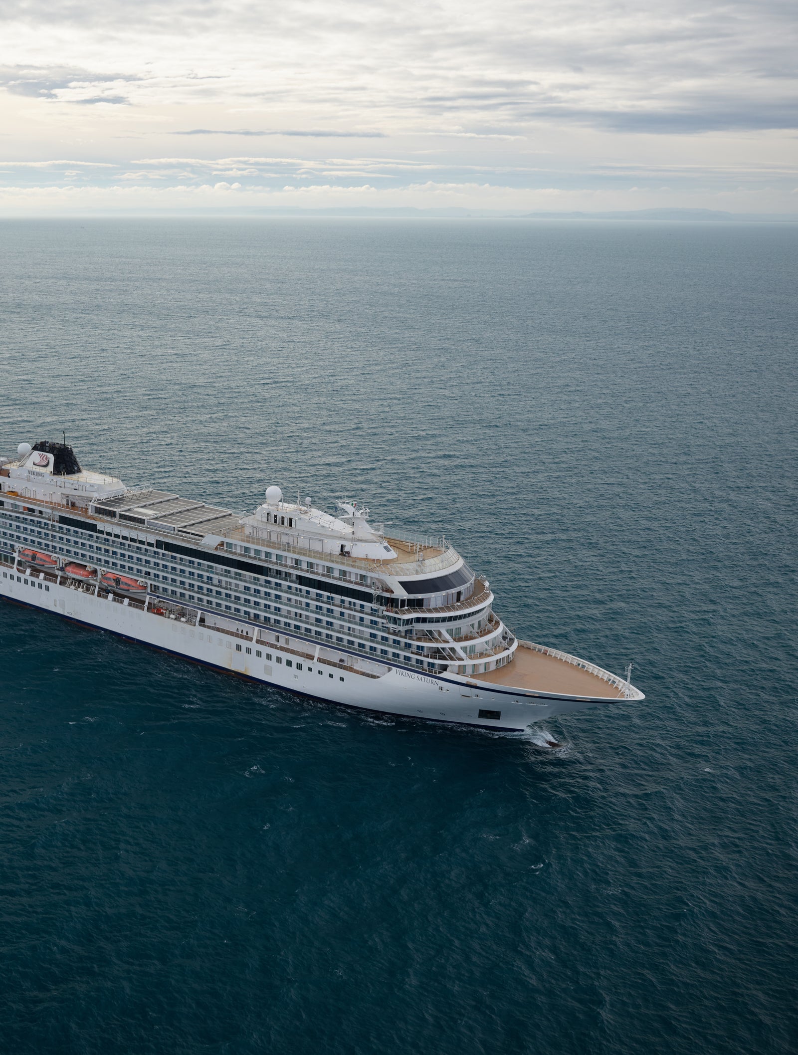 Fincantieri | Group - Business - Products - Cruise Ships - Viking Sun: Large modern cruise ship in operation navigating calm ocean waters under cloudy sky, multiple decks and expansive outdoor spaces, setting highlights sea vastness and ship’s grandeur.