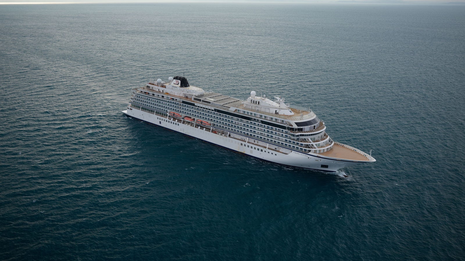 Fincantieri | Group - Business - Products - Cruise Ships - Viking Sun: Large modern cruise ship in operation navigating calm ocean waters under cloudy sky, multiple decks and expansive outdoor spaces, setting highlights sea vastness and ship’s grandeur.