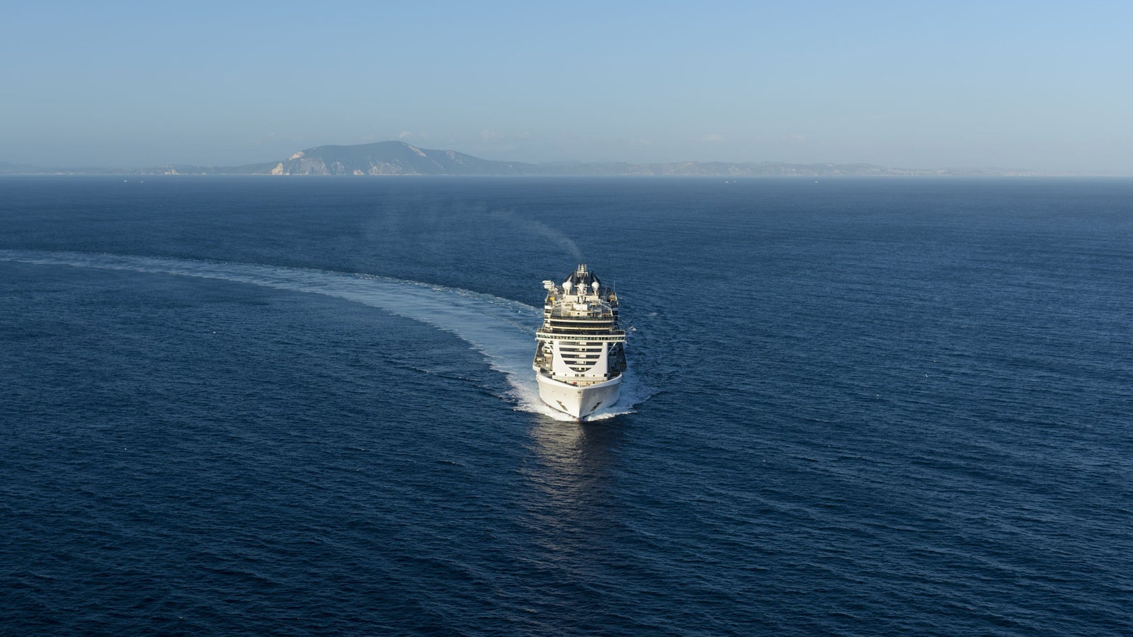 Fincantieri | Group - Business - Products - Cruise Ships - MSC Seaside: Distant view of MSC Seaside cruise ship in operation, multi-level structure and visible decks, coastal background.