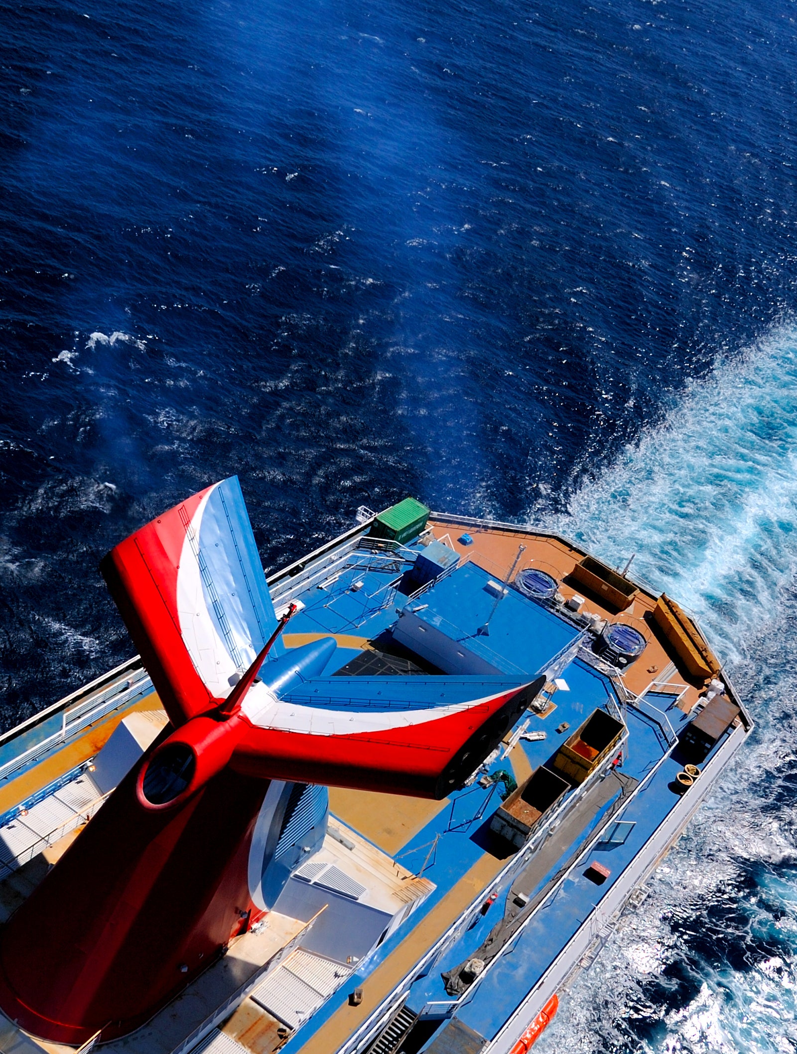Fincantieri | Group - Business - Products - Cruise Ships - Carnival Splendor: Overhead view of Carnival Splendor cruise ship in operation sailing on clear blue waters under sunny sky, detail of aft deck and prominent red funnel.