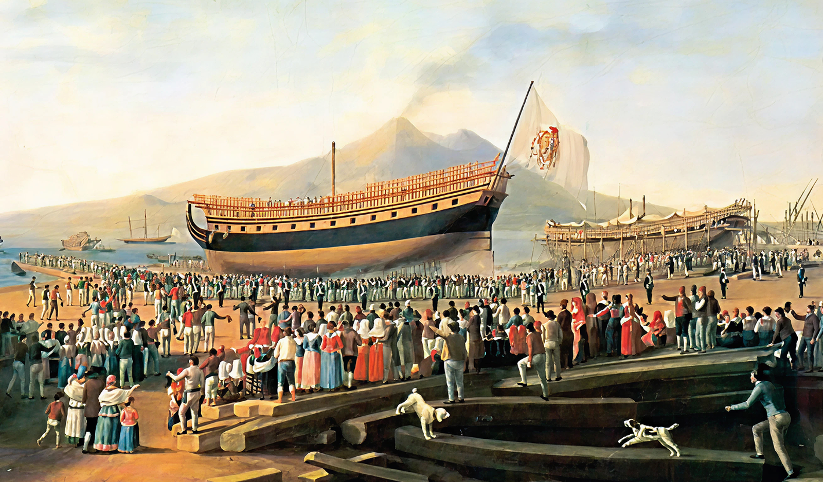 Fincantieri | About Us - Heritage and Future: Historic launch event with a large crowd on the shore, wooden ship with elaborate details and a flag with emblem, people of various ages and clothing, dogs and mountains in the background, ceremonial atmosphere.