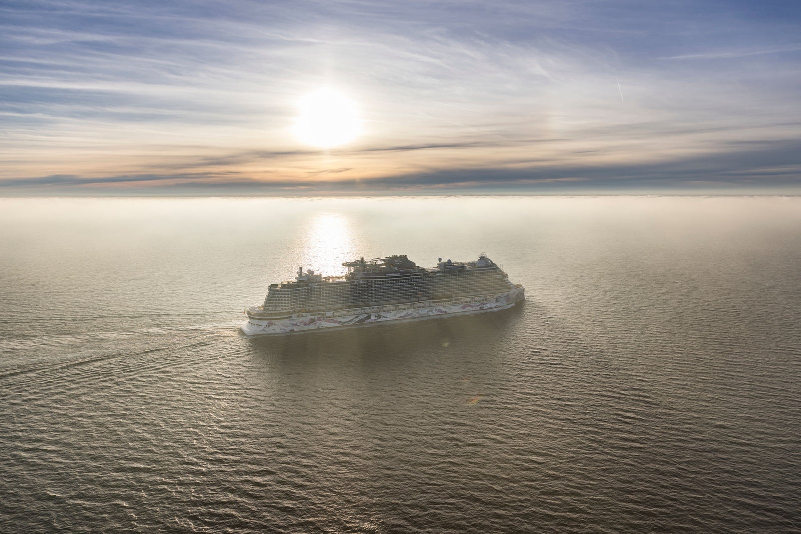  Fincantieri | Gruppo - Business - Prodotti - Navi da Crociera - Norwegian Luna: Nave da crociera di lusso in navigazione, molteplici ponti, dettagli di design intricati, ampie aree ricreative all’aperto, scafo decorato con opere d’arte colorate dall’aspetto distintivo e vivace.