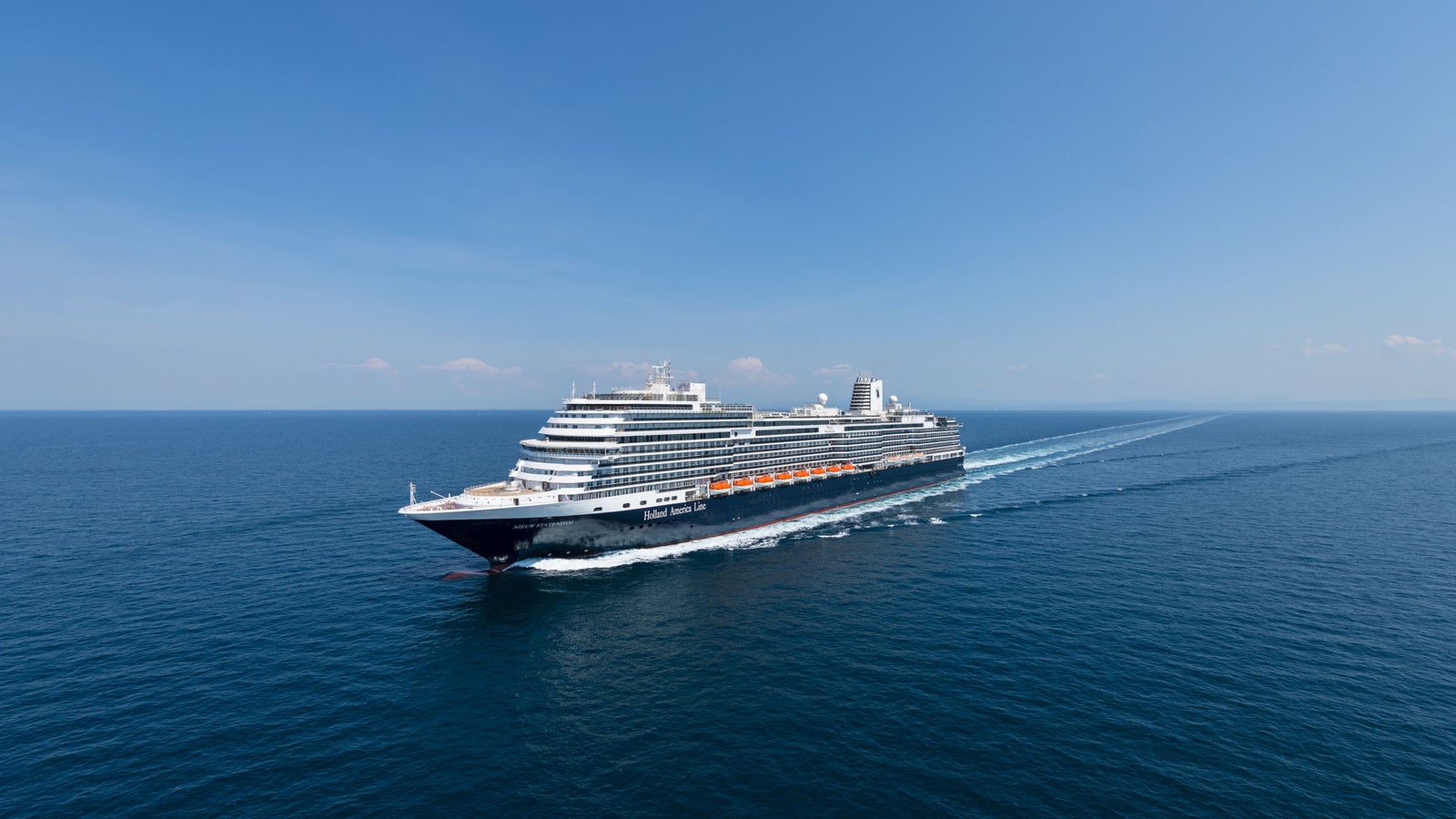 Fincantieri | Gruppo - Business - Prodotti - Navi da Crociera - Nieuw Statendam: Grande nave da crociera moderna operativa che scivola su mare calmo e aperto sotto cielo azzurro limpido, più ponti e design elegante, atmosfera di maestosità e avventura.