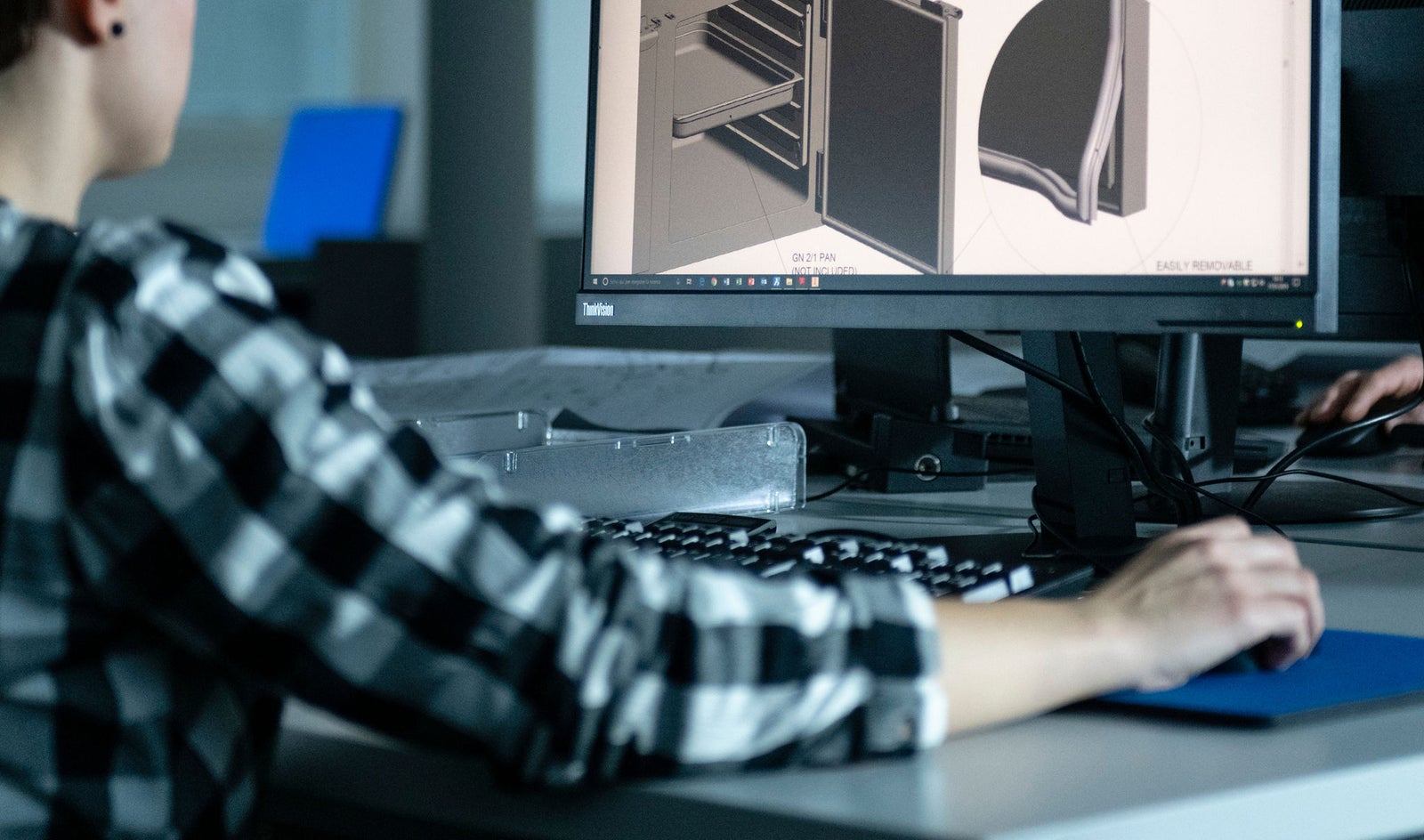 Suppliers and Partners – Fincantieri | Partnership: Person sitting at a desk using 3D modeling software on a computer, with detailed technical designs featuring sections and components on the screen, modern office or studio environment focused on design and engineering, 2nd Fincantieri Supplier Summit.