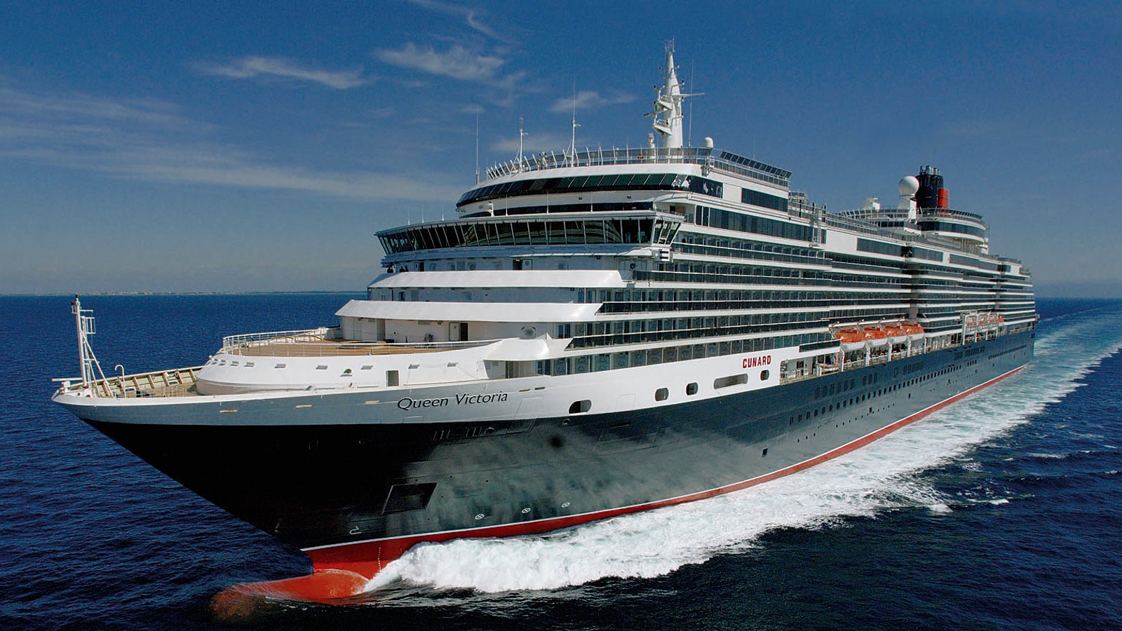 Fincantieri | Group - Business - Products - Cruise Ships - Queen Victoria: View of Queen Victoria cruise ship in operation navigating open sea, hull with distinctive black, white and red livery, multiple passenger decks, Queen Victoria name visible on hull.