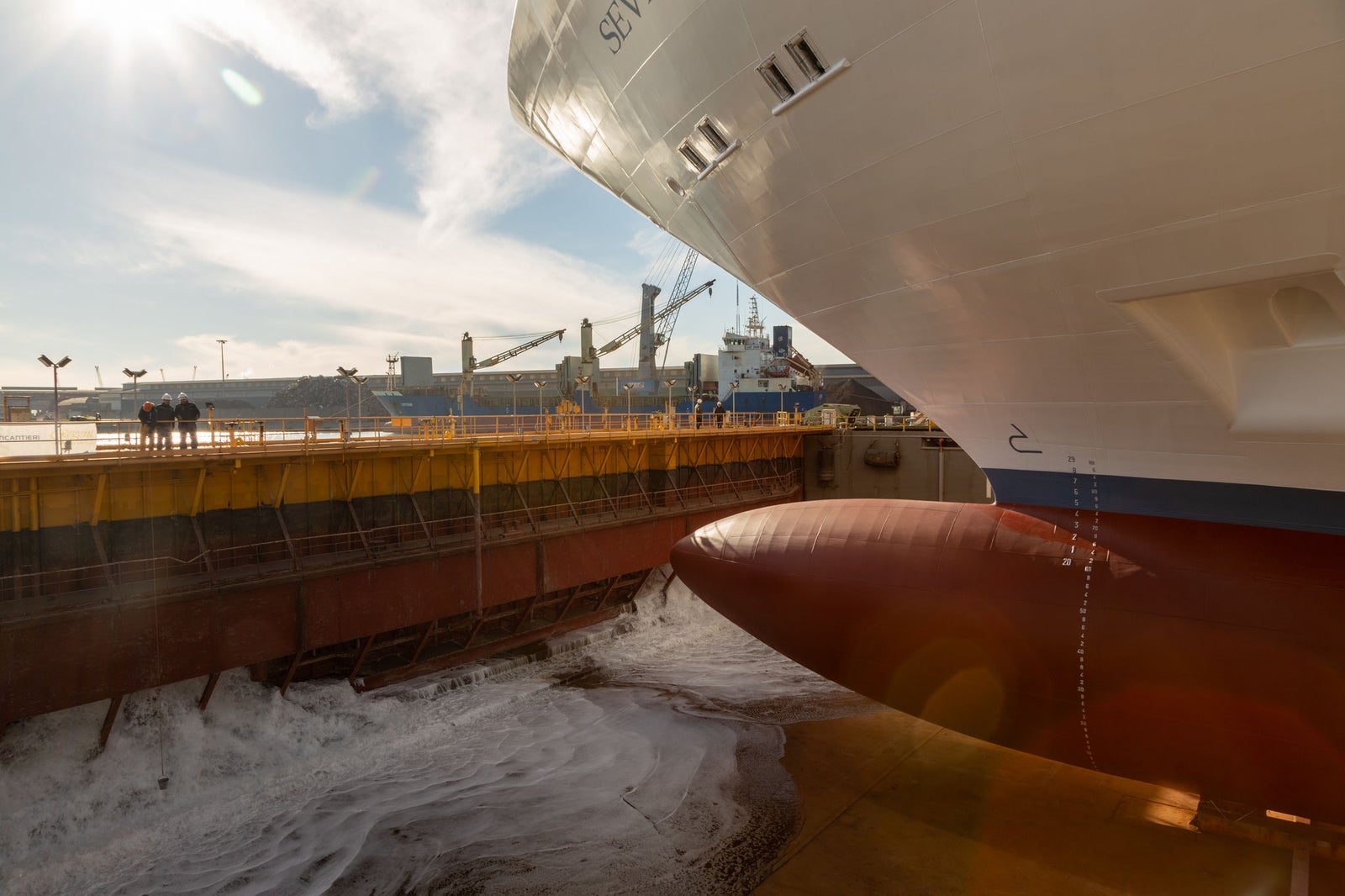 newsroom - press releases - 2025 - fincantieri group: fincantieri seven seas prestige launched in marghera: bow and bulbous bow of the "seven seas prestige" in the Marghera shipyard dock during launch, shipyard staff and cranes in the background.