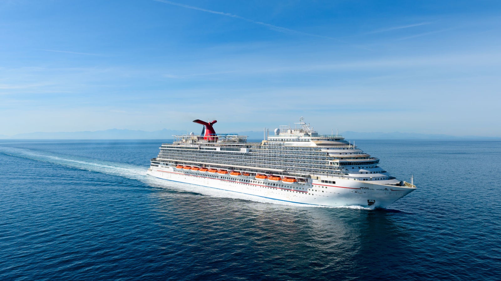 Fincantieri | Group - Business - Products - Cruise Ships - Viking Jupiter: Large modern cruise ship in operation gliding through calm ocean waters under cloudy sky, multiple decks and sleek architecture, setting emphasizes ship’s grandeur and sea vastness.