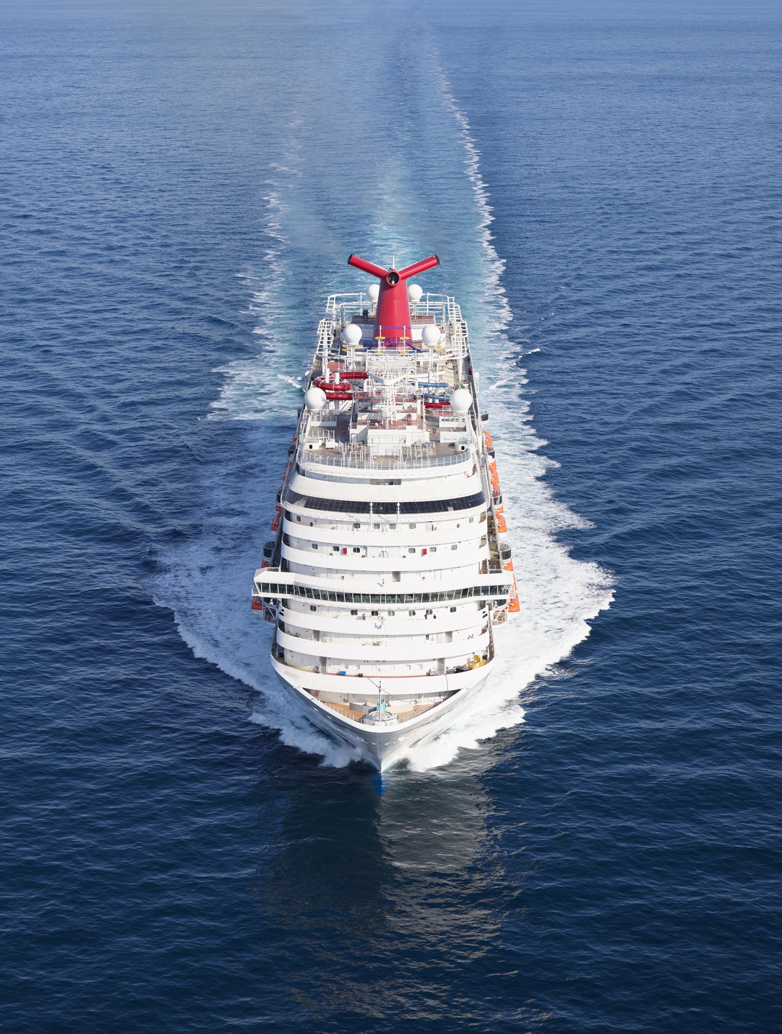 Fincantieri | Gruppo - Business - Prodotti - Navi da Crociera - Carnival Panorama: Grande nave da crociera operativa in navigazione su acque oceaniche blu profonde e calme sotto cielo parzialmente nuvoloso, fumaiolo rosso caratteristico e molteplici ponti, ambiente sereno che sottolinea relax e avventura.