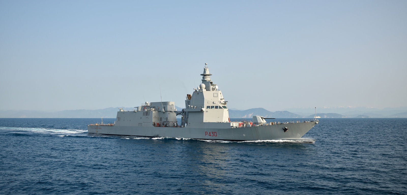 Fincantieri | Gruppo - Business - Prodotti - Navi per la difesa - Fregate - Classe Thaon de Revel: Vista laterale della nave operativa in navigazione, scafo moderno con numero P430 visibile, sfondo terre emerse distanti.