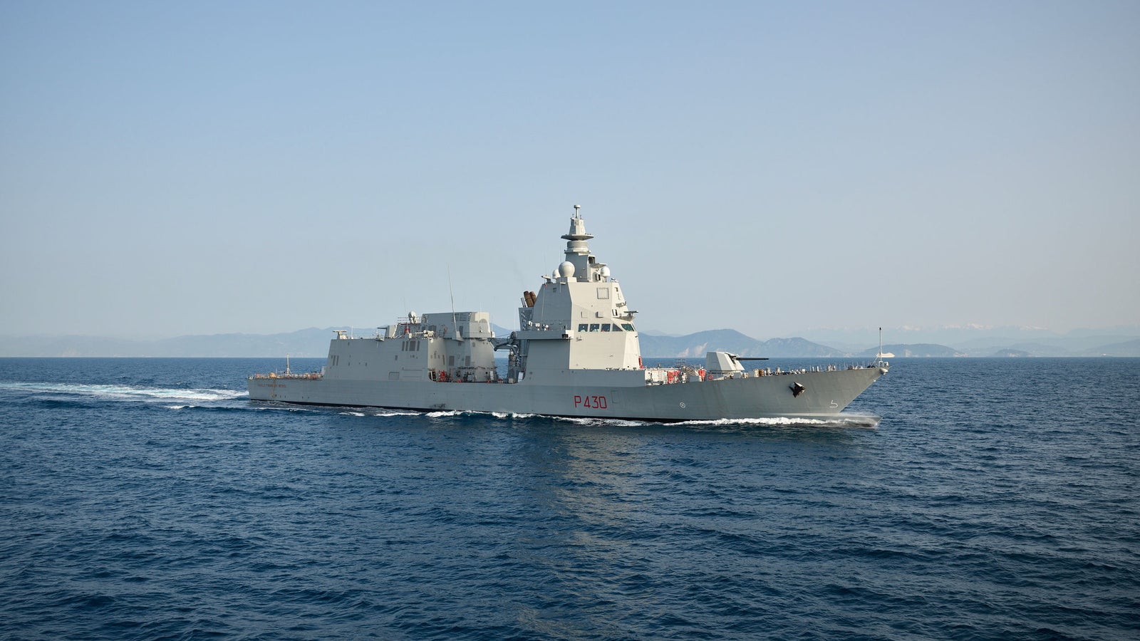 Fincantieri | Gruppo - Business - Prodotti - Navi per la difesa - Fregate - Classe Thaon de Revel: Vista laterale della nave operativa in navigazione, scafo moderno con numero P430 visibile, sfondo terre emerse distanti.