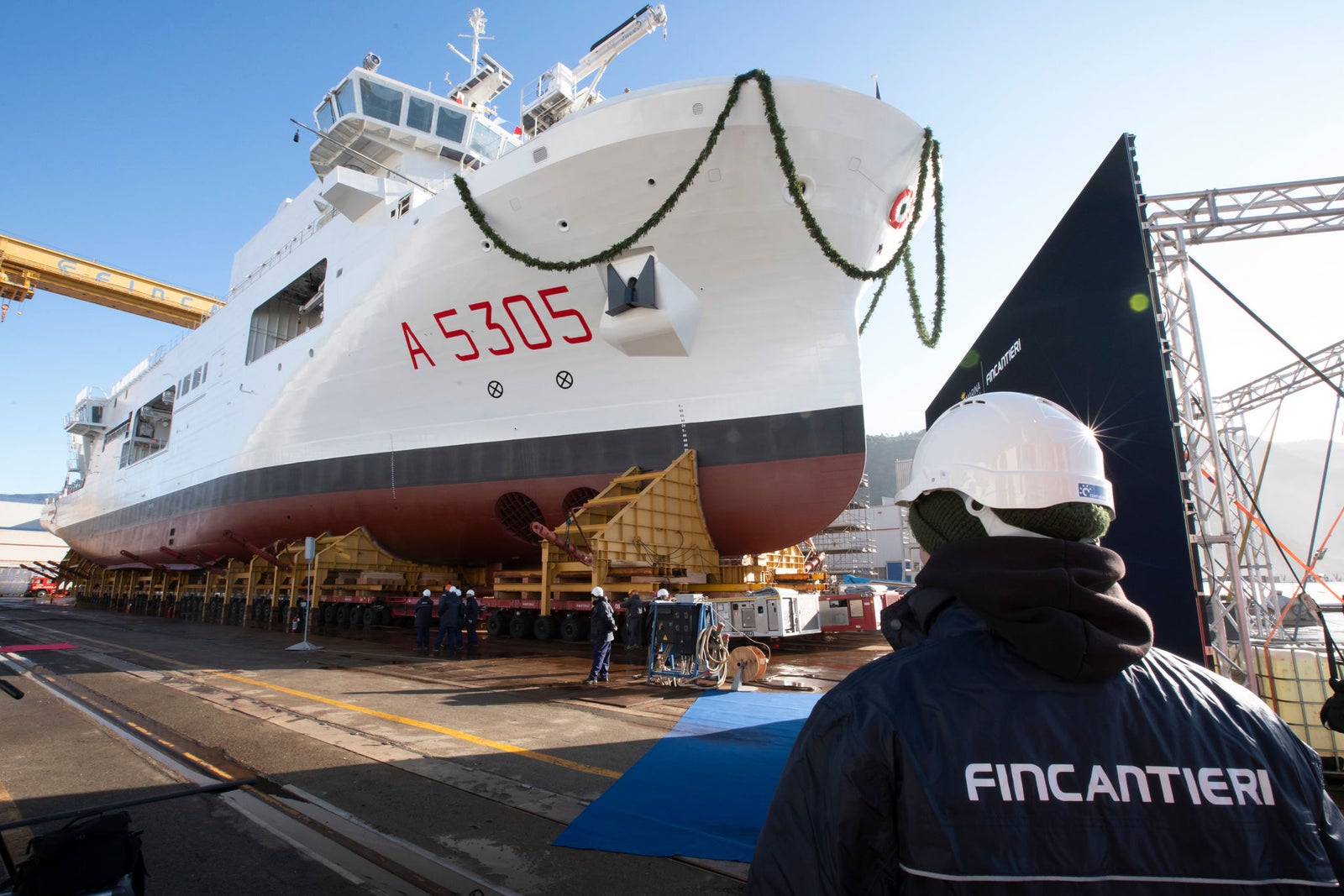 Newsroom - Press releases - 2026 - Fincantieri Group: Launch of the Italian Navy's "Quirinale" major hydro-oceanographic ship: italian navy hydro-oceanographic ship "quirinale" a5305 decorated for launch, viewed from bow with fincantieri worker in foreground.