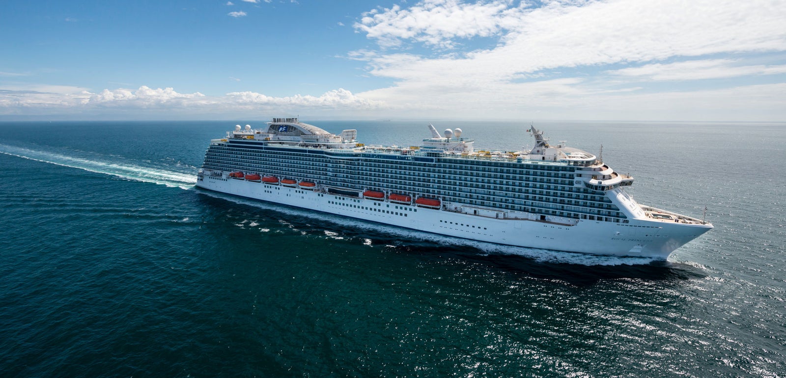 Fincantieri | Group - Business - Products - Cruise Ships - Royal Princess: Large luxury cruise ship in operation gliding on calm sea waters under partly cloudy sky, multiple decks, lifeboats, elegant white exterior.