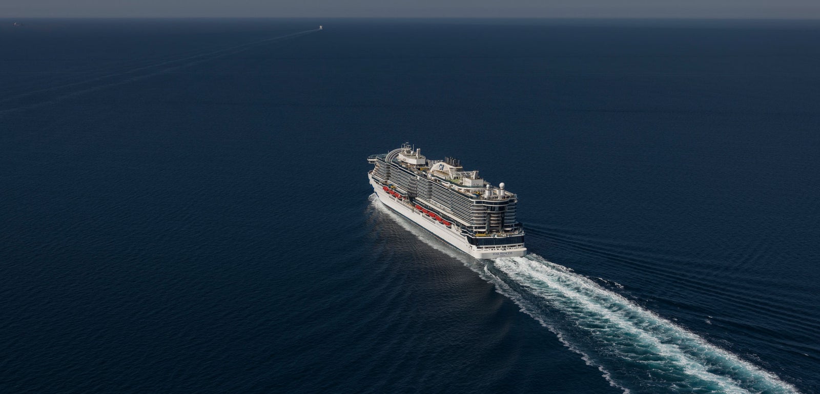  Fincantieri | Gruppo - Business - Prodotti - Navi da Crociera - Star Princess: Massive cruise ship in operation, navigating calm open ocean waters, visible wake, multiple decks, sleek design, clear blue sky.