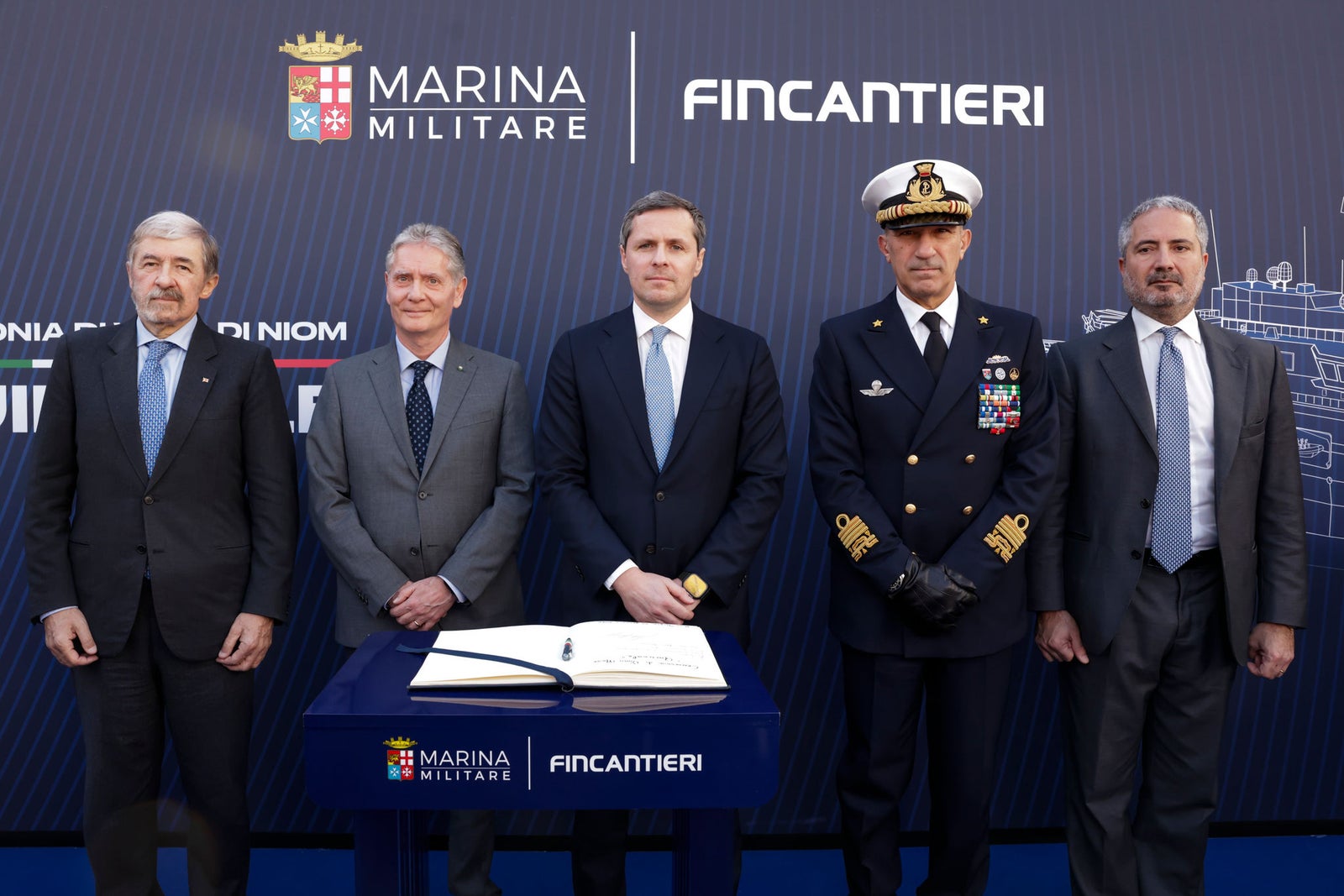 Newsroom - Press releases - 2026 - Fincantieri Group: Launch of the Italian Navy's "Quirinale" major hydro-oceanographic ship: representatives from the italian navy and fincantieri stand in front of partnership backdrop at event table with guest book.