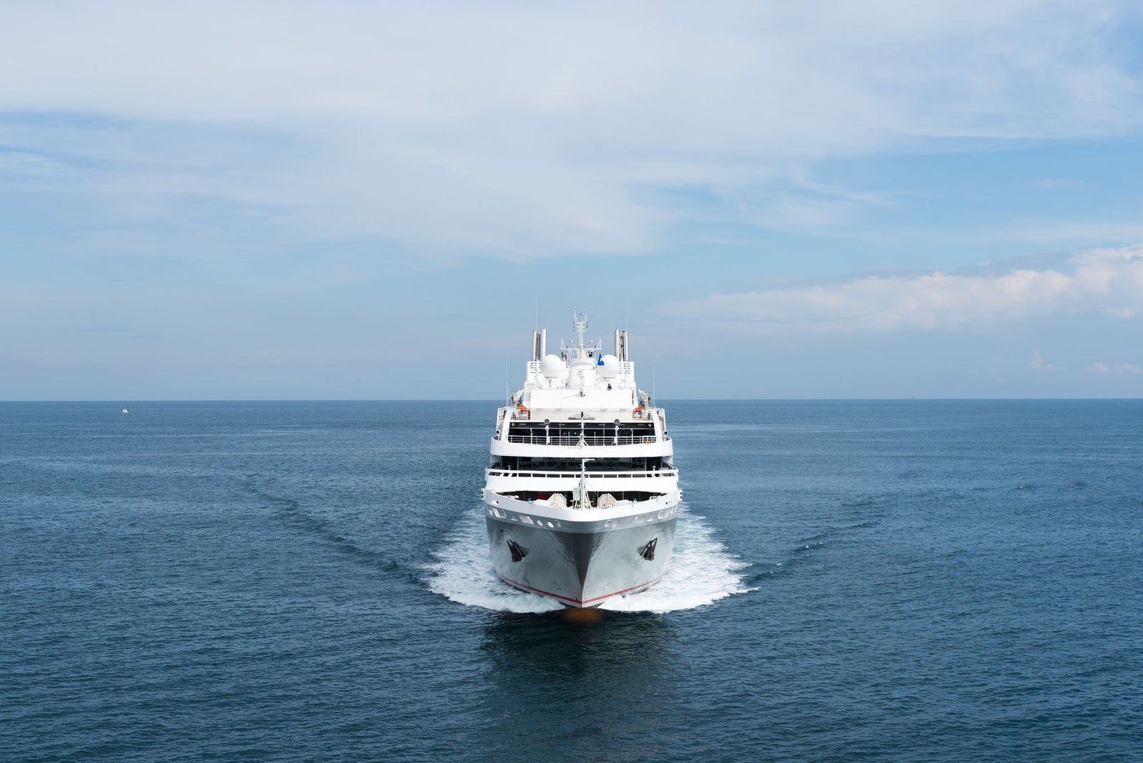 Fincantieri | Group - Business - Products - Cruise Ships - Le Soléal: Large white cruise ship in operation sailing forward on calm open waters under partly cloudy sky, multiple decks and sleek design suggest luxurious travel experience, serene ocean setting emphasizes relaxation and adventure.