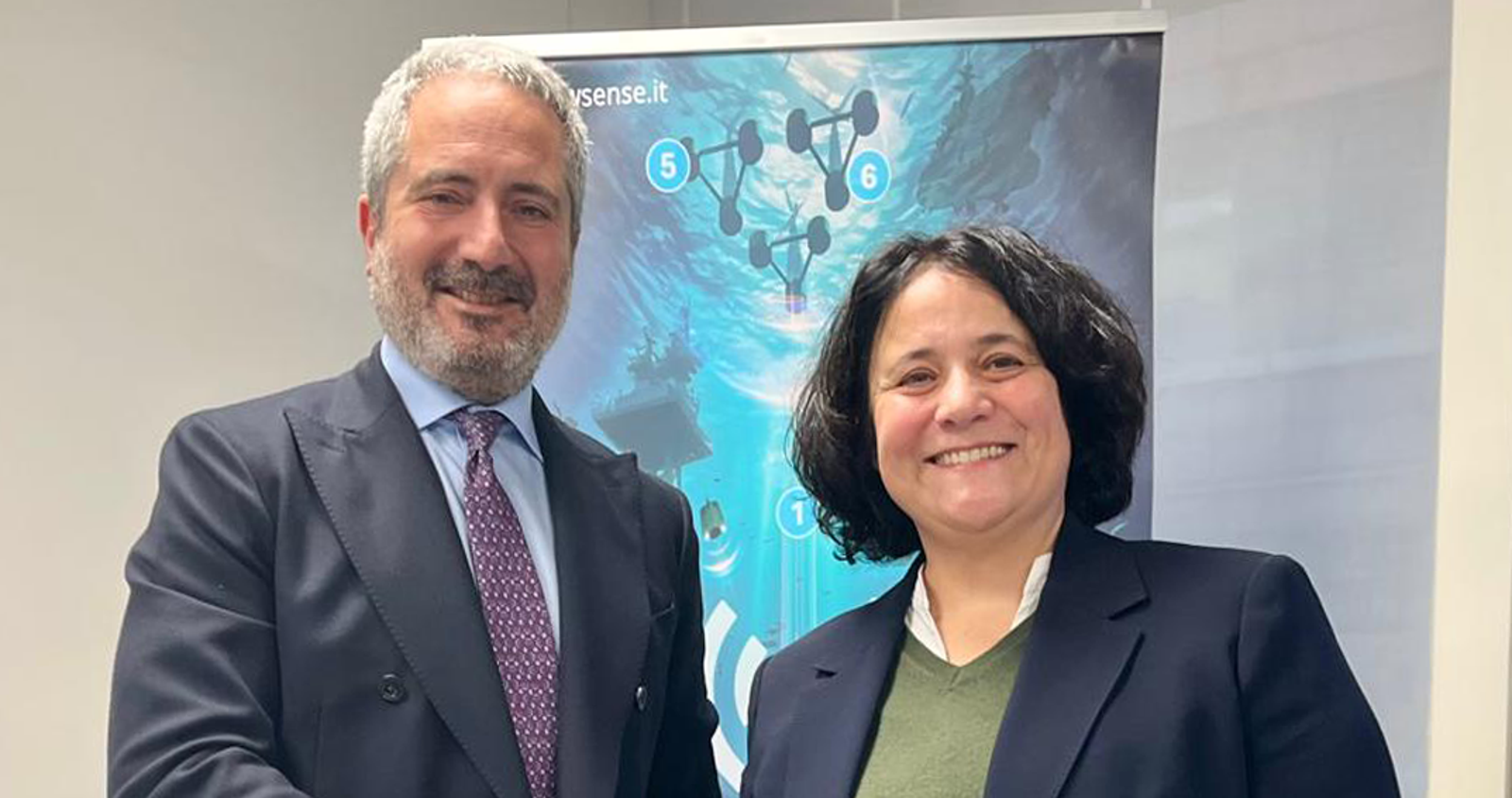Newsroom - Press releases - 2026 - Fincantieri Group: agreement with WSense for the co-development of technological and commercial wireless solution: fincantieri and wsense managers in business suits shake hands in front of a marine technology display.