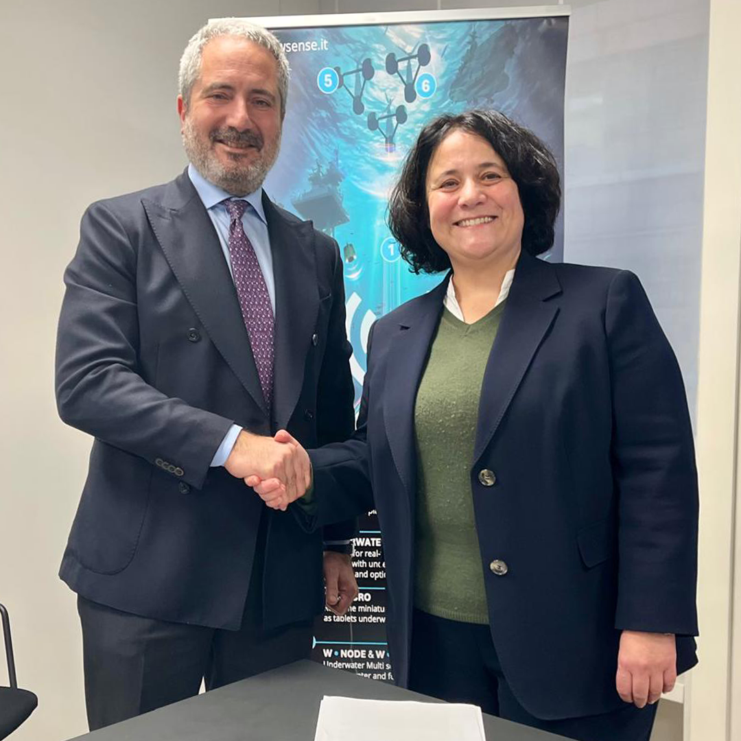 Newsroom - Press releases - 2026 - Fincantieri Group: agreement with WSense for the co-development of technological and commercial wireless solution: fincantieri and wsense managers in business suits shake hands in front of a marine technology display.