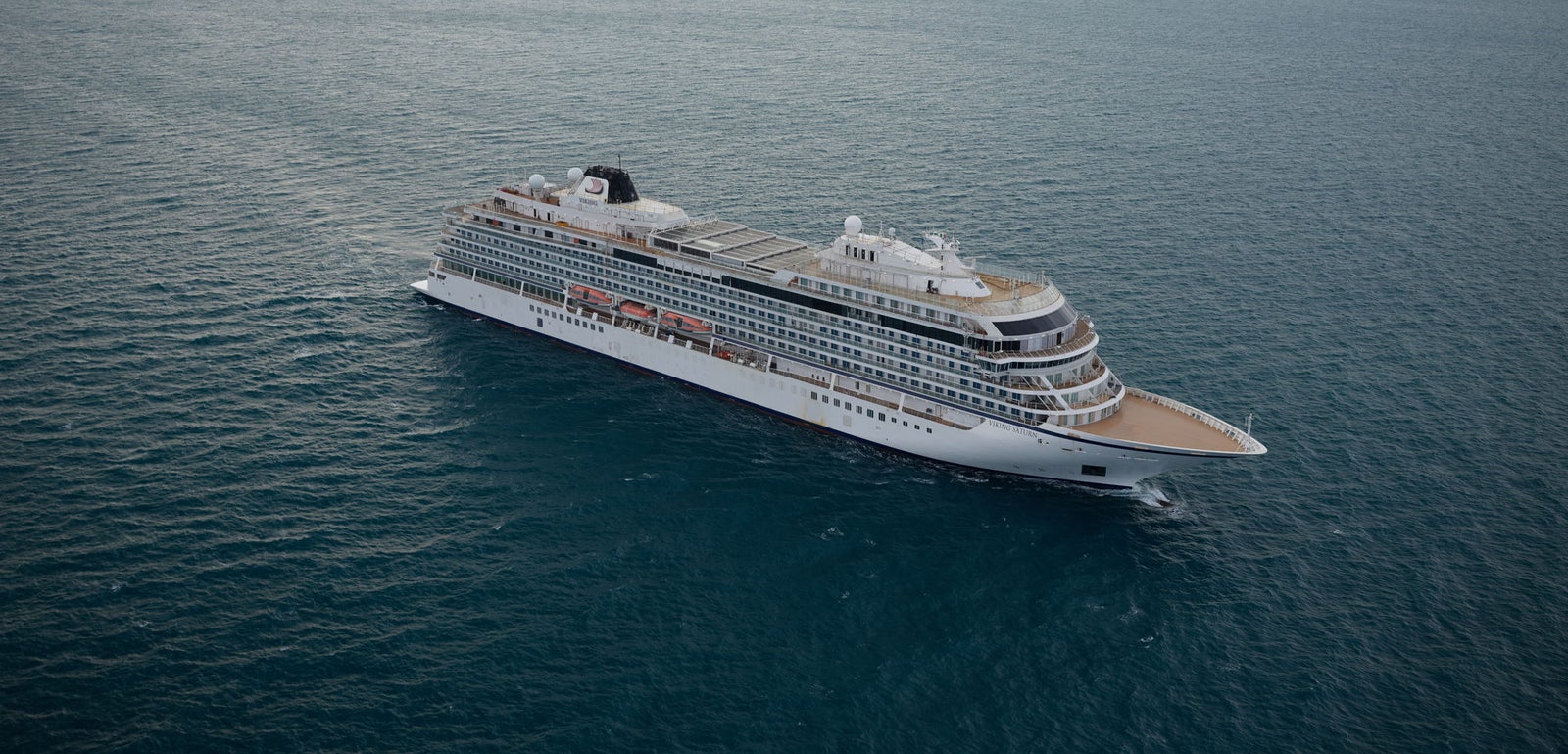  Fincantieri | Group - Business - Products - Cruise Ships - Viking Saturn: Large modern cruise ship in operation, navigating calm ocean waters under cloudy sky, multiple decks and expansive outdoor spaces, setting highlights sea vastness and ship’s grandeur.