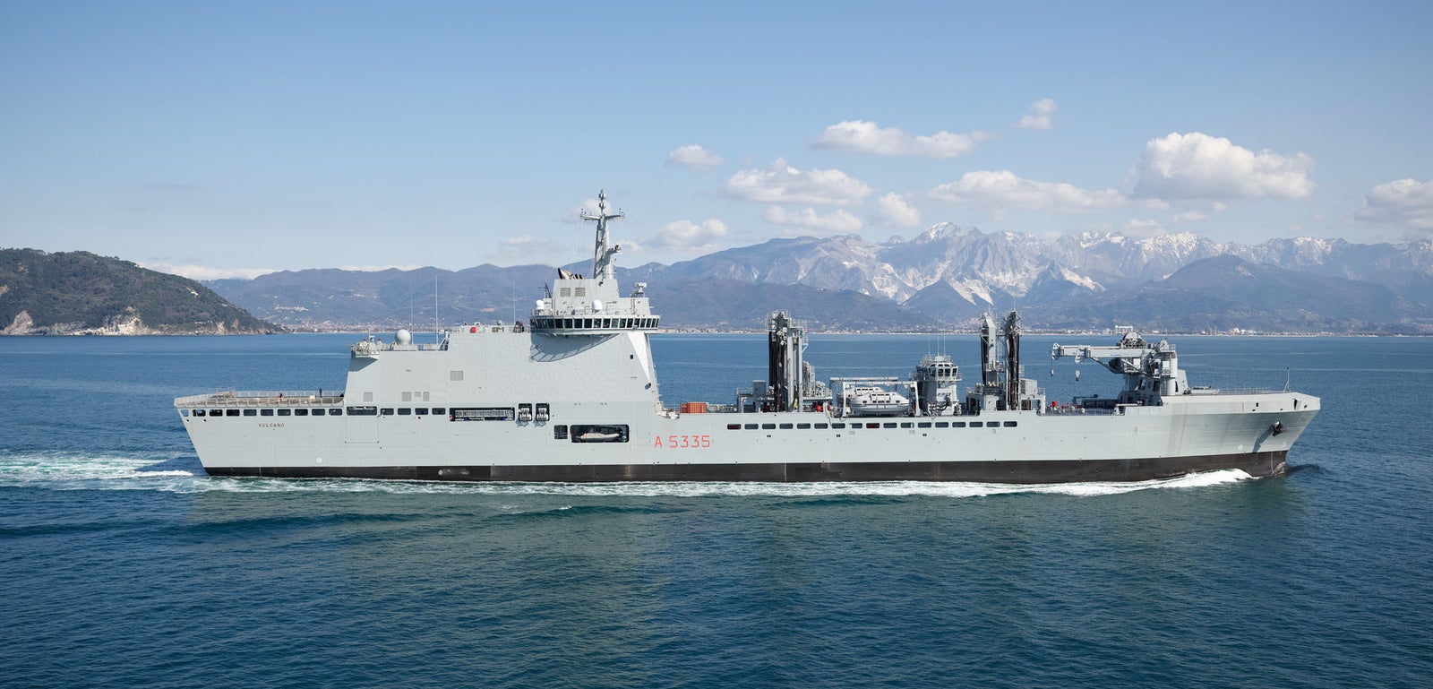  Fincantieri | Gruppo - Business - Prodotti - Navi Logistiche e di Rifornimento - Classe Vulcano: Vista laterale della nave LSS Vulcano operativa in navigazione, design moderno, equipaggiamento per operazioni marittime, sfondo con montagne innevate e cielo sereno.