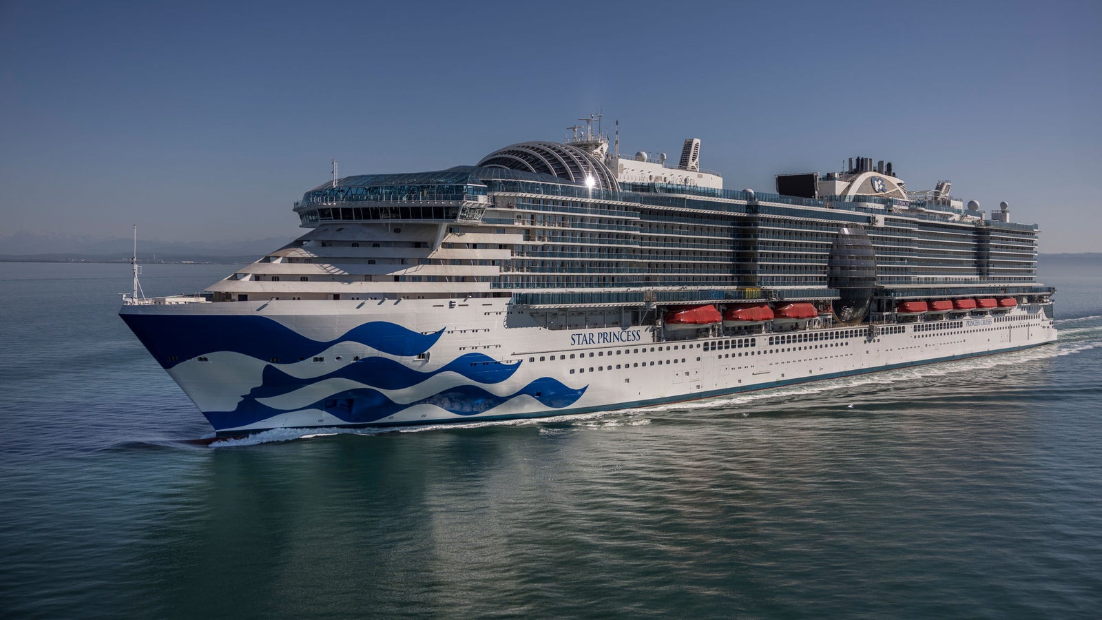 Fincantieri | Gruppo - Business - Prodotti - Navi da Crociera - Star Princess: Star Princess cruise ship in operation, sailing on calm clear waters, sleek hull with distinctive wave pattern, bright blue sky overhead.