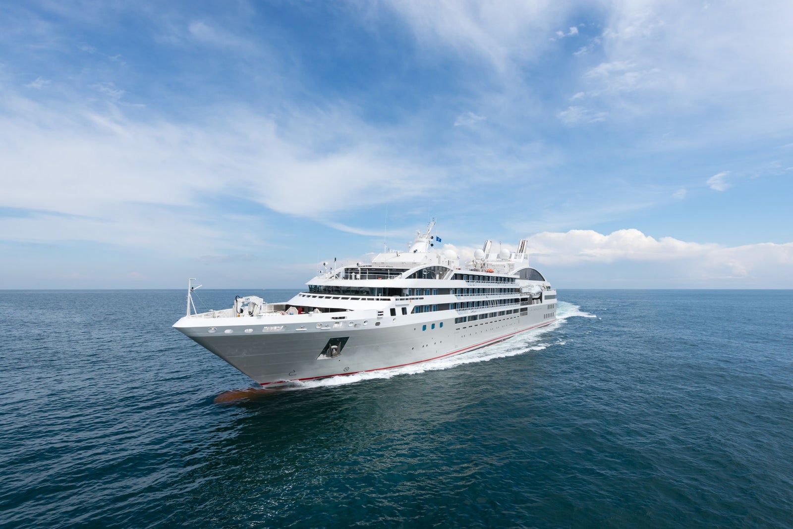 Fincantieri | Group - Business - Products - Cruise Ships - Le Soléal: Modern white cruise ship in operation gliding across calm blue waters under partly cloudy sky, multiple decks and sleek design suggest premium travel experience, serene ocean setting highlights ship’s grandeur and journey.