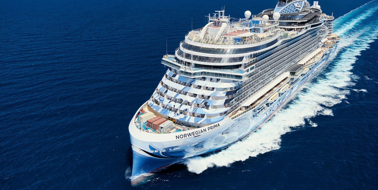Fincantieri | Group - Business - Products - Cruise Ships - Norwegian Prima: Side view of Norwegian Prima cruise ship in operation, multiple decks, modern design, Norwegian Prima branding clearly visible on hull.
