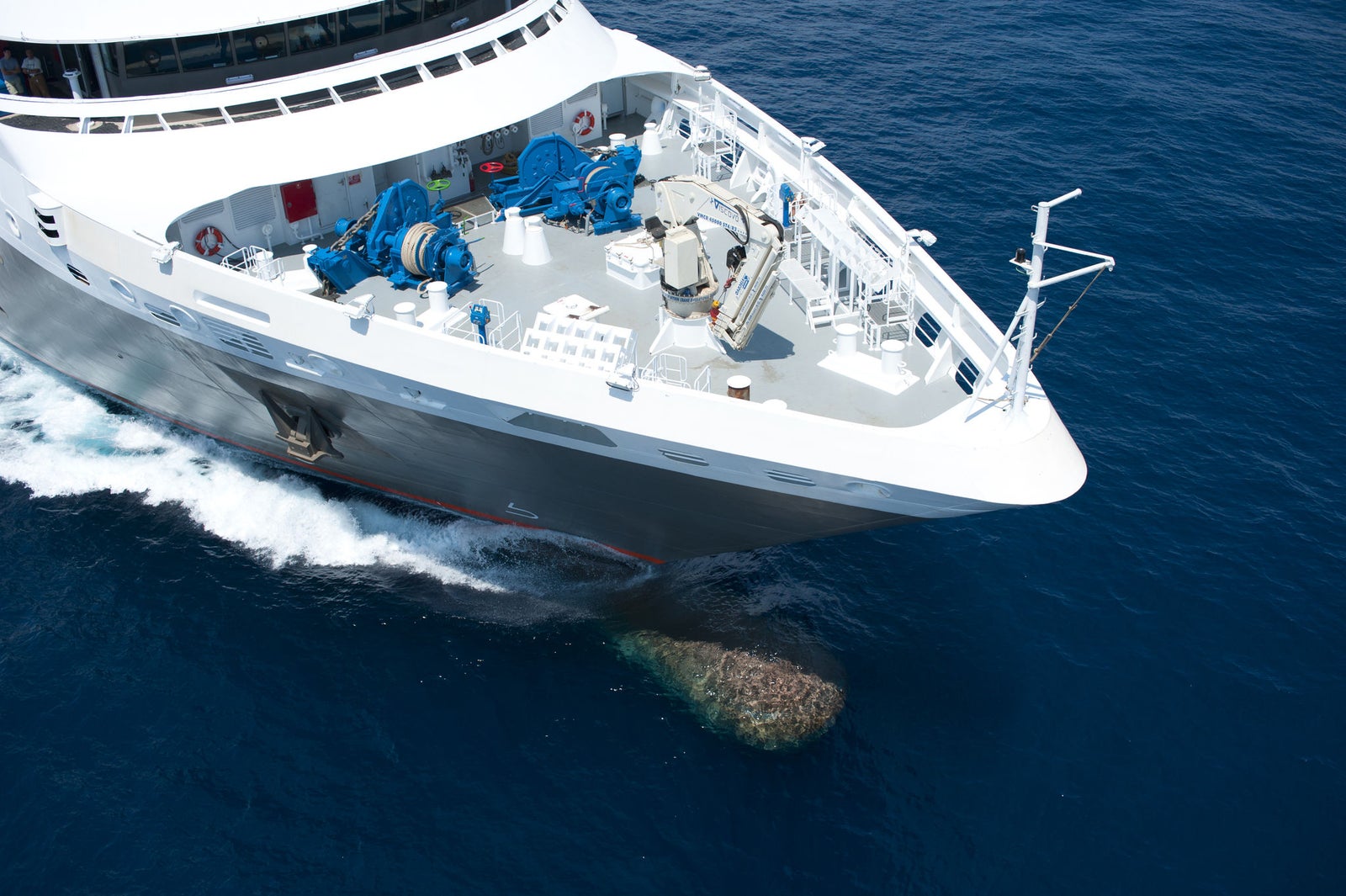  Fincantieri | Group - Business - Products - Cruise Ships - L'Austral: Large white cruise ship in operation crossing deep blue ocean waters, streamlined exterior, advanced deck machinery and navigation instruments visible, calm surroundings create peaceful atmosphere, technical features highlight operational capabilities.