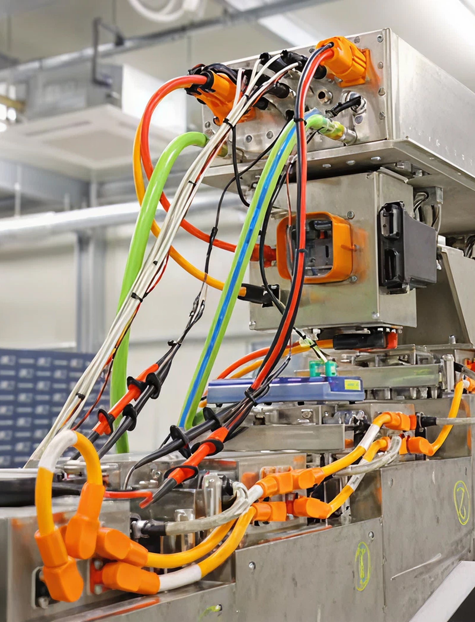 Fincantieri | Group - Subsidiaries and Affiliates - Power4Future: Close-up of industrial machinery featuring complex arrangement of colorful cables and connectors; modern manufacturing or laboratory environment, visible metal components and wiring; bright orange, green, and black wires stand out against metallic structure.