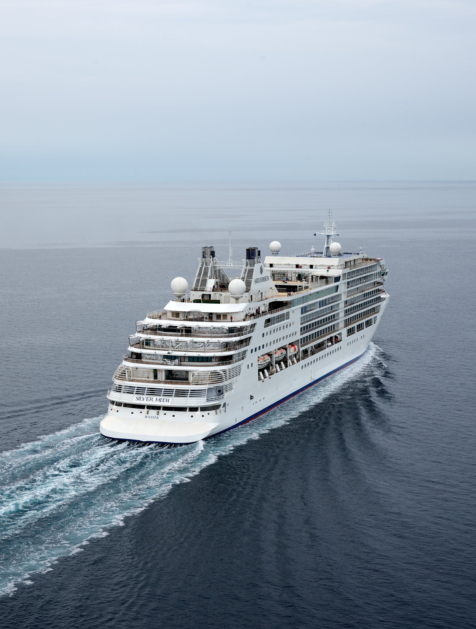  Fincantieri | Gruppo - Business - Prodotti - Navi da Crociera - Silver Moon: Vista di poppa della nave Silver Moon operativa in navigazione, scafo bianco con ponti passeggeri multilivello e scialuppe di salvataggio visibili.