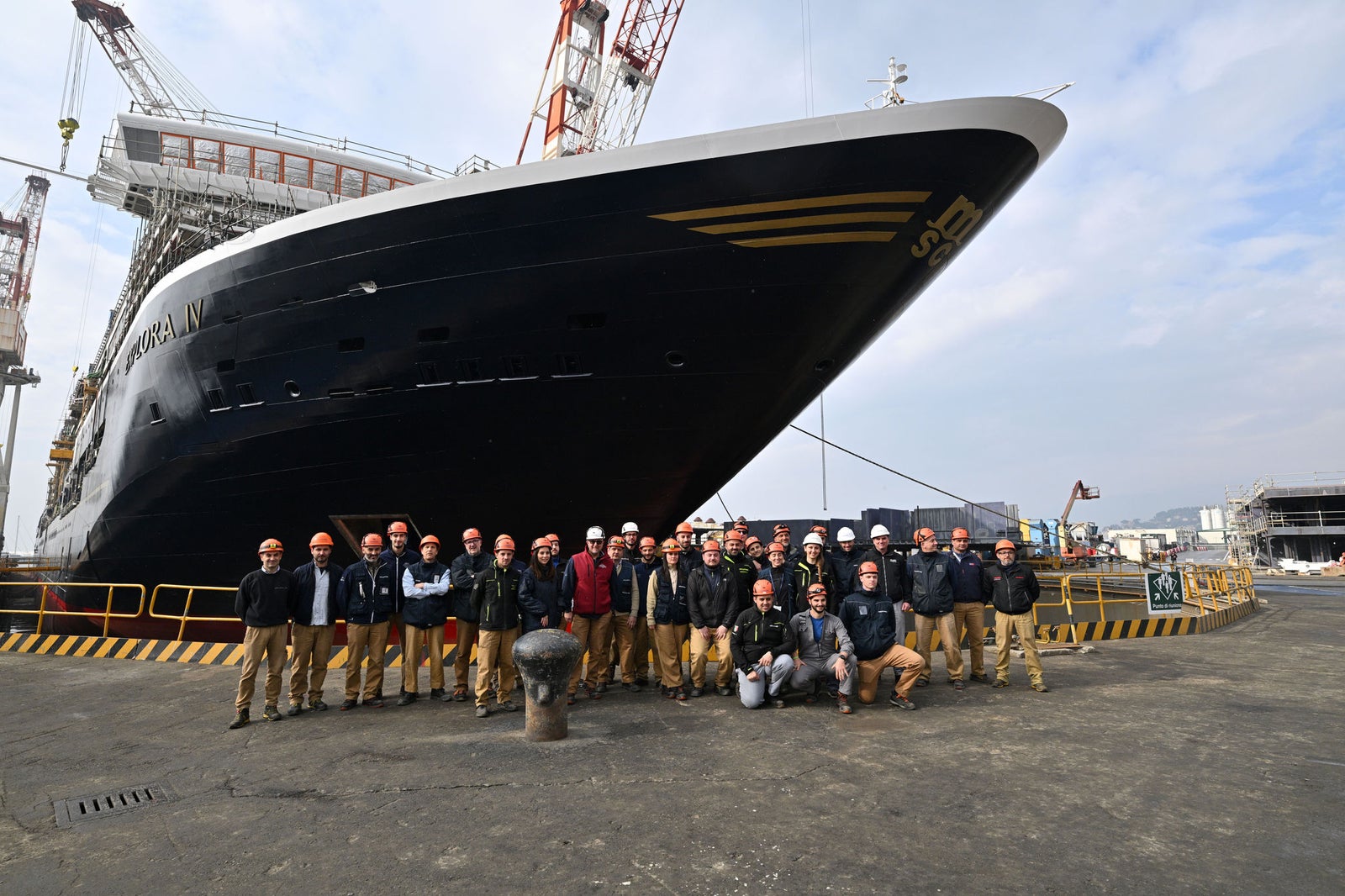 Newsroom - Press releases - 2026 - Fincantieri Group: Fincantieri:  Today triple ceremony for Fincantieri and Explora Journeys at Sestri Ponente: launche of Explora IV, coin ceremony for Explora V and steel cuttingfor Explora VI: Workers and engineers with helmets pose in front of the bow of Explora IV cruise ship at Sestri Ponente shipyard.