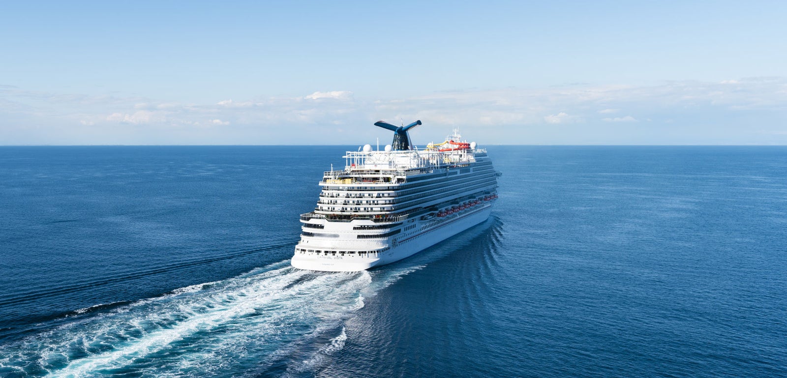 Fincantieri | Group - Business - Products - Cruise Ships - Carnival Vista: Large operational cruise ship navigating vast open ocean under clear blue sky, visible wake highlighting movement and speed, distinctive funnel design, multiple decks indicating luxurious travel experience.