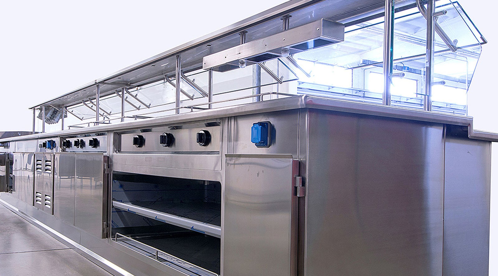 Fincantieri | Group - Subsidiaries and Affiliates - Seanergy: Modern commercial kitchen setup with stainless steel equipment, multiple ovens and control knobs; professional food preparation area, clean industrial design, bright lighting emphasizes reflective surfaces and functional layout.